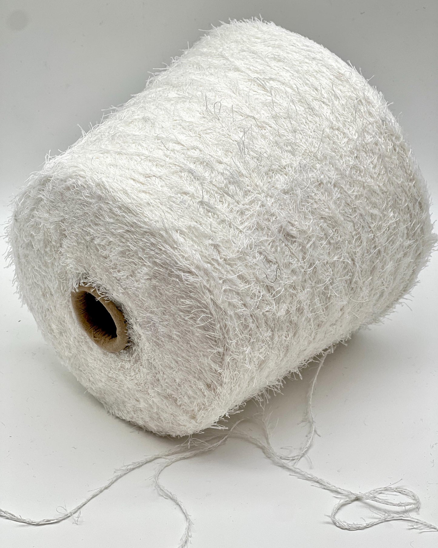 Spool of white yarn on a light gray background
