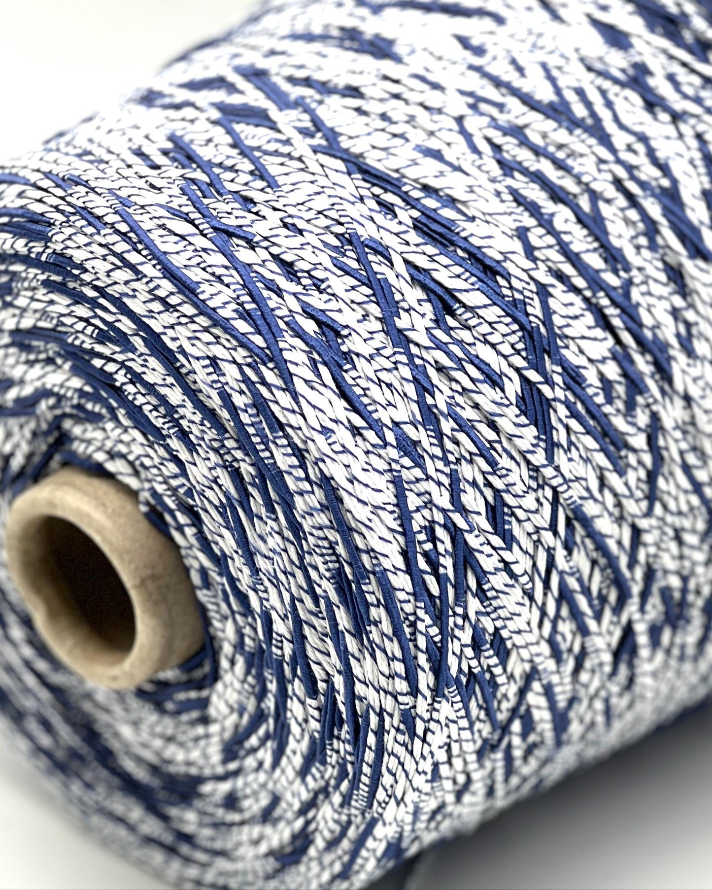 Close-up of a spool of blue and white yarn on a light background