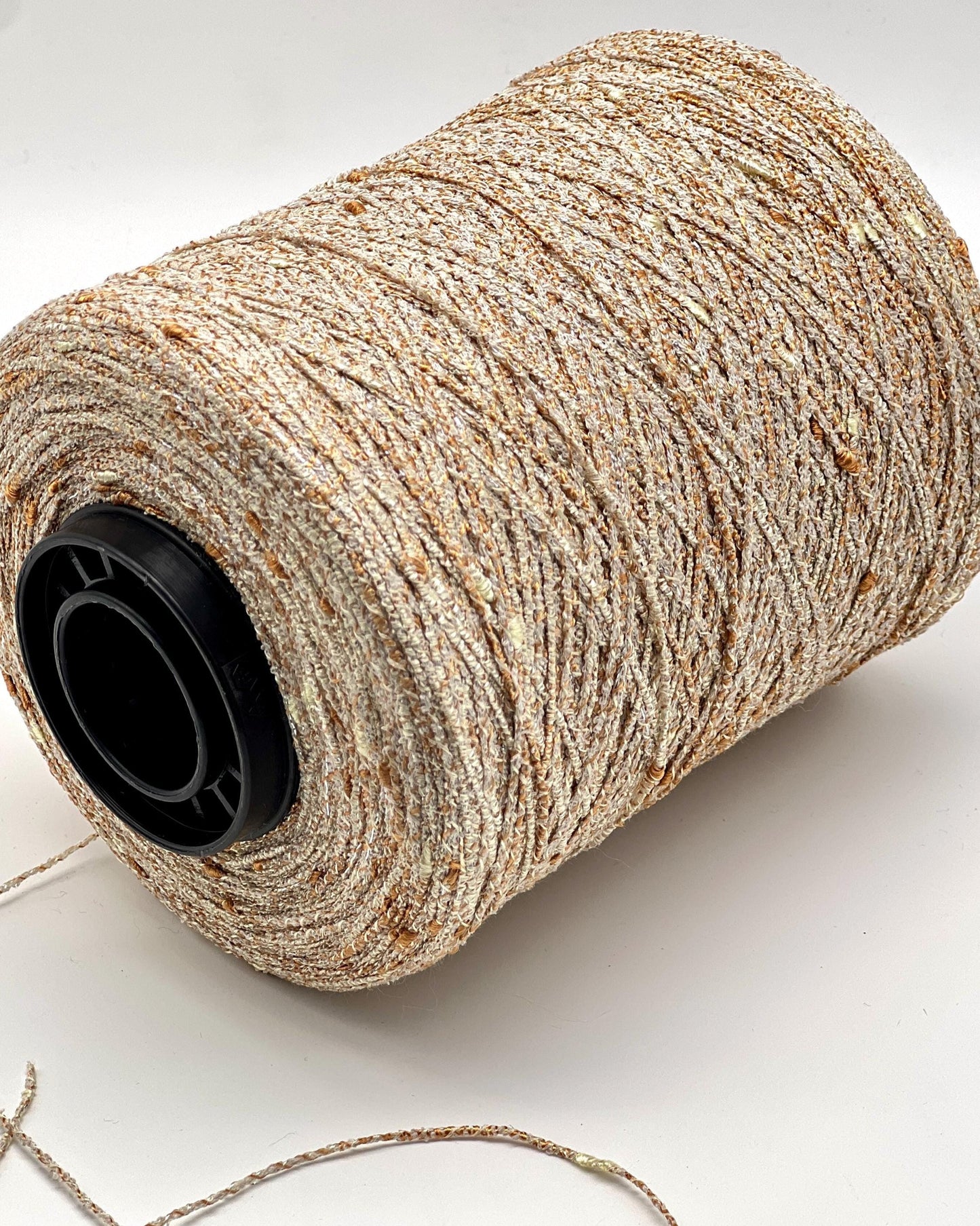Spool of beige thread with a black core on a white background