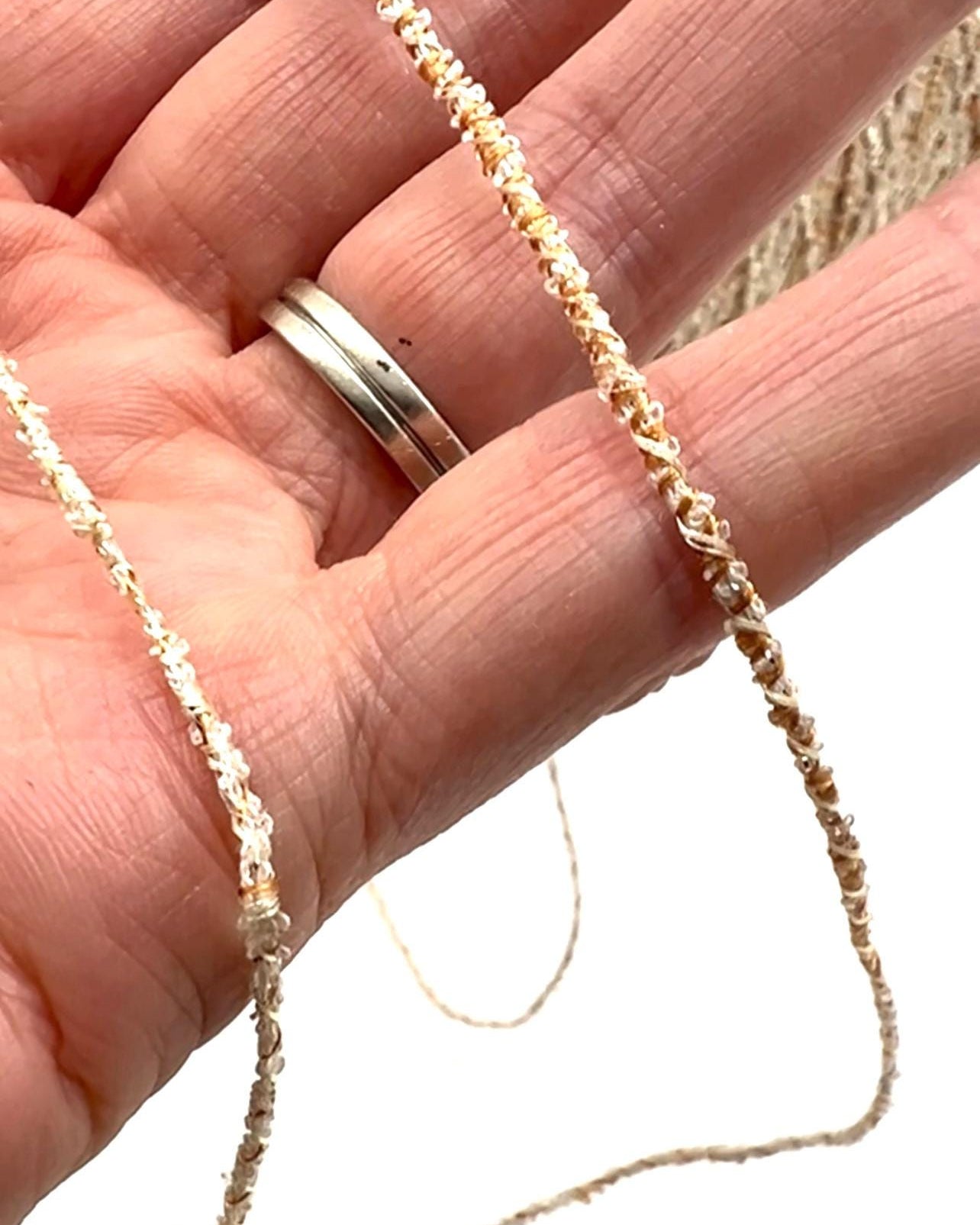 Hand holding a delicate beaded necklace with a blurred background