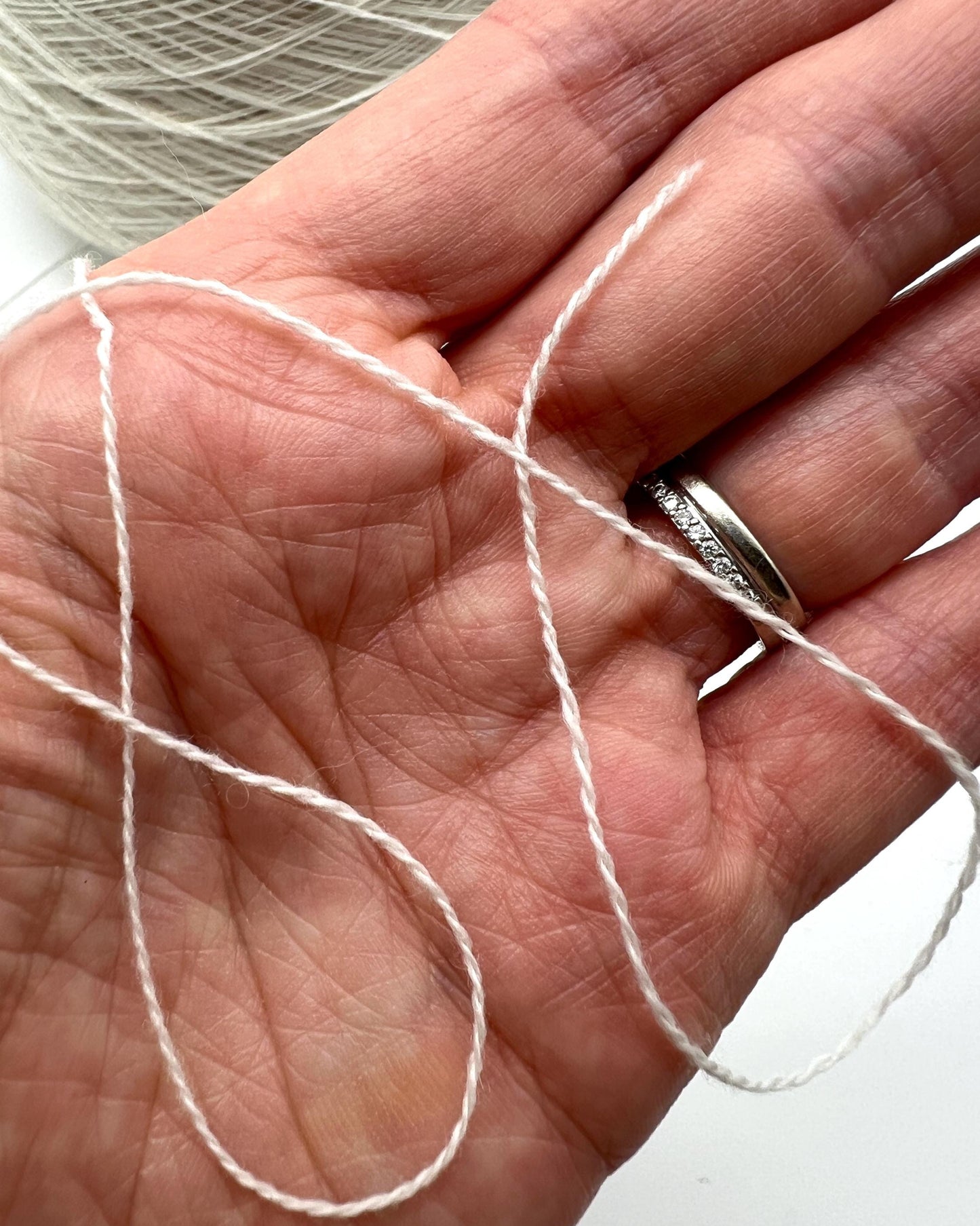 Hand holding a ball of white yarn with a close-up view