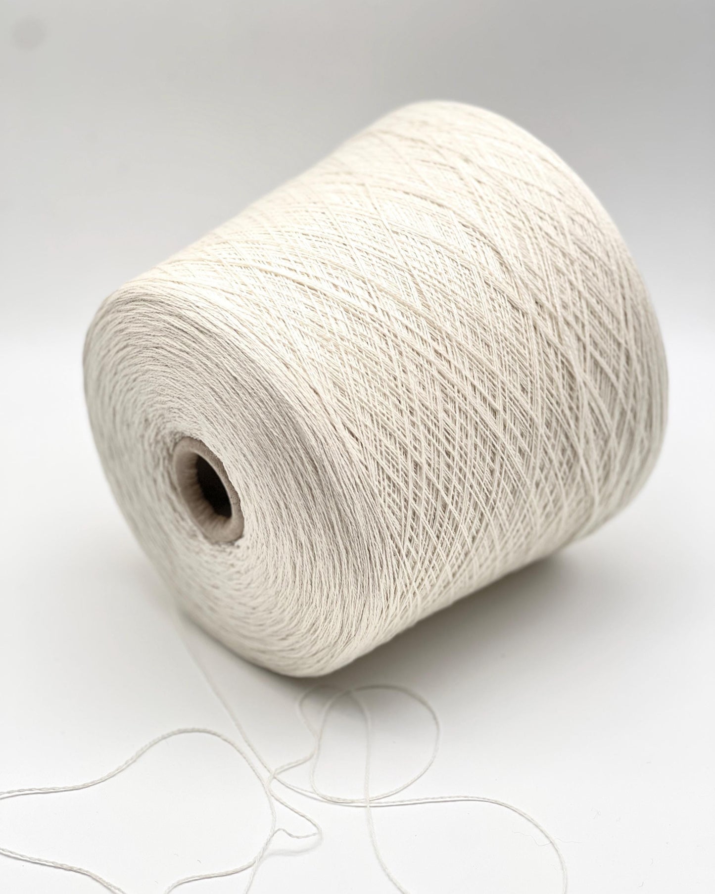 Large spool of white yarn on a light gray background
