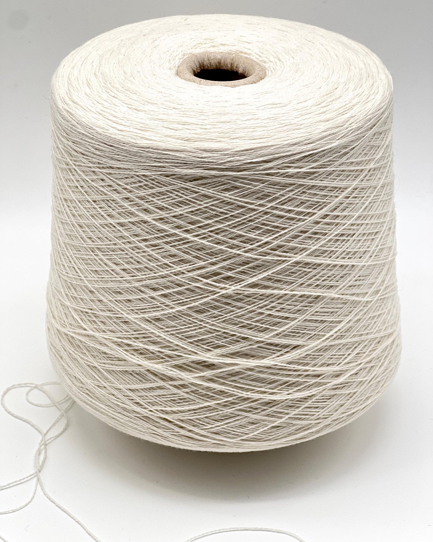 Spool of white yarn on a light gray background