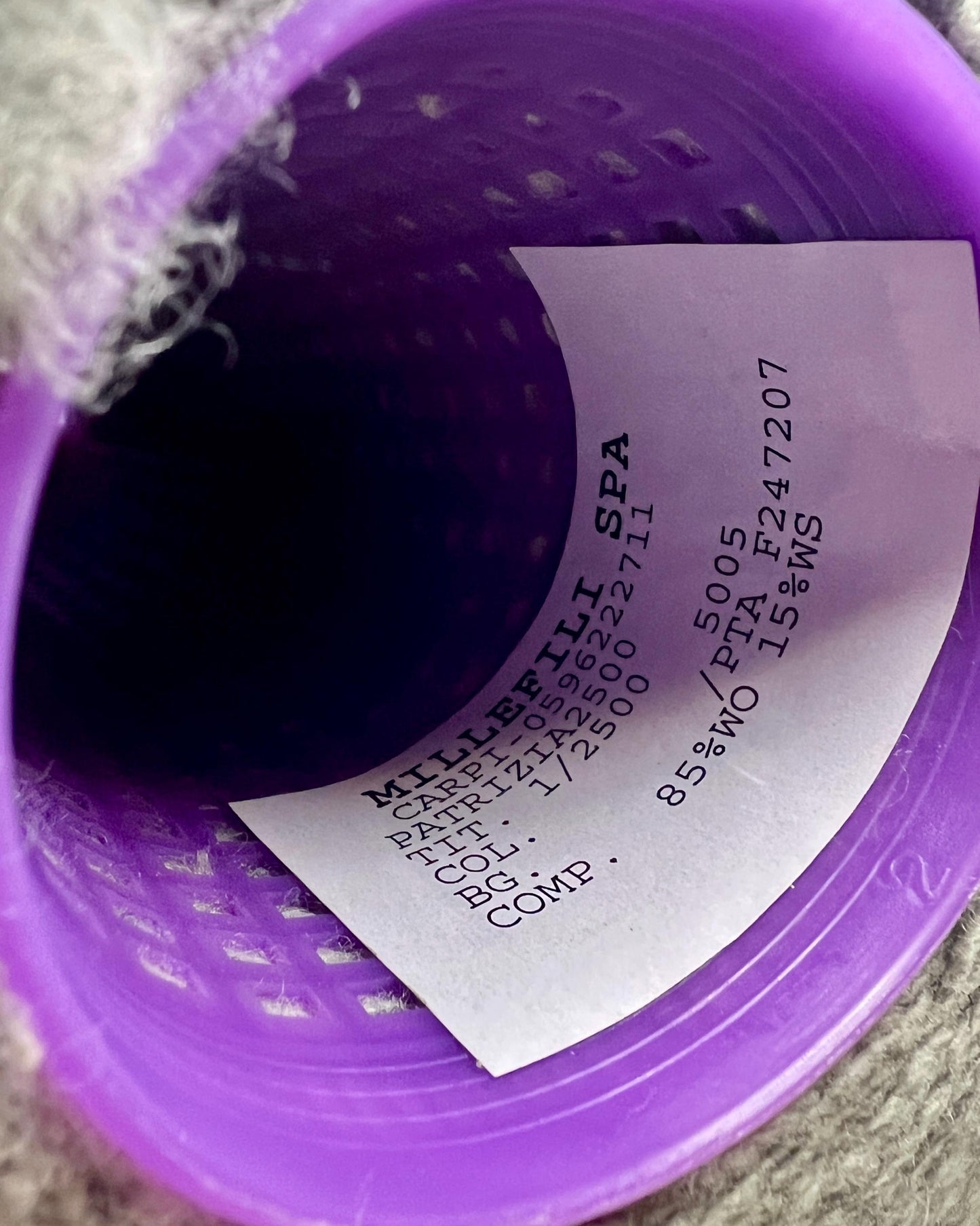 Purple container with a label inside, on a textured surface