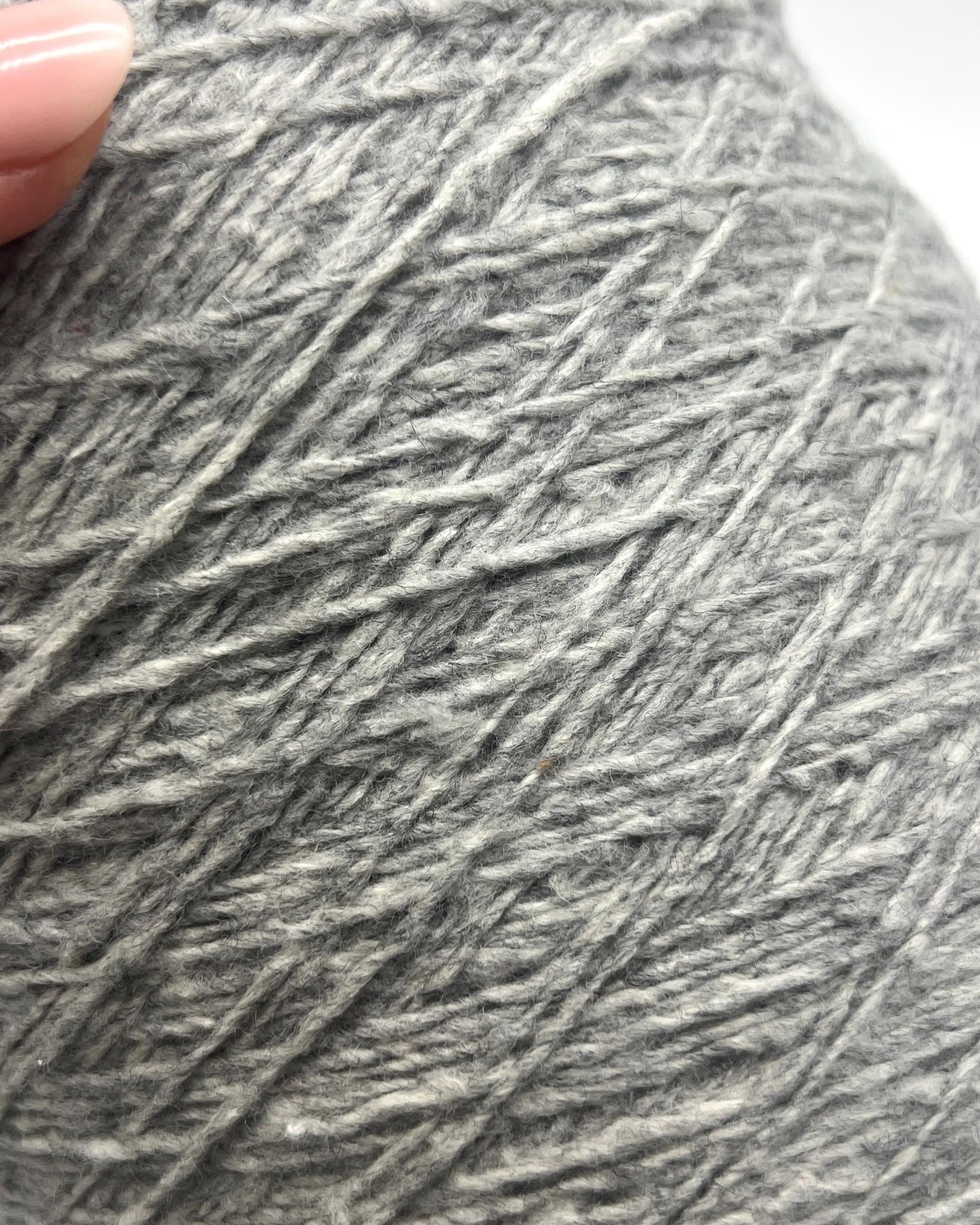 Close-up of a gray skein of yarn held by a hand.