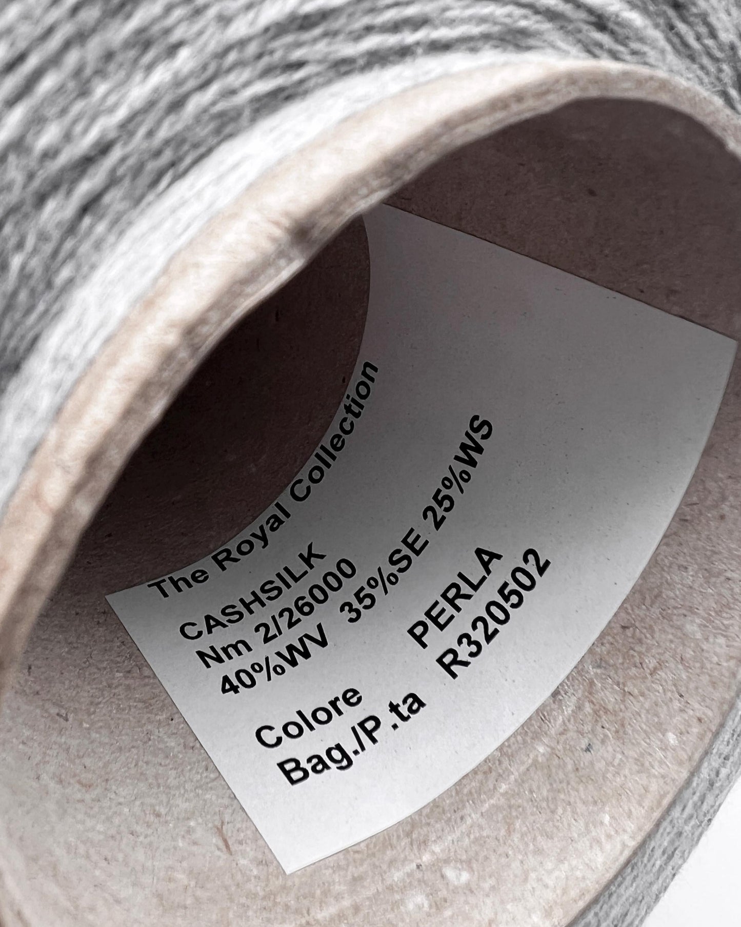Close-up of a spool of yarn with a label on a white background