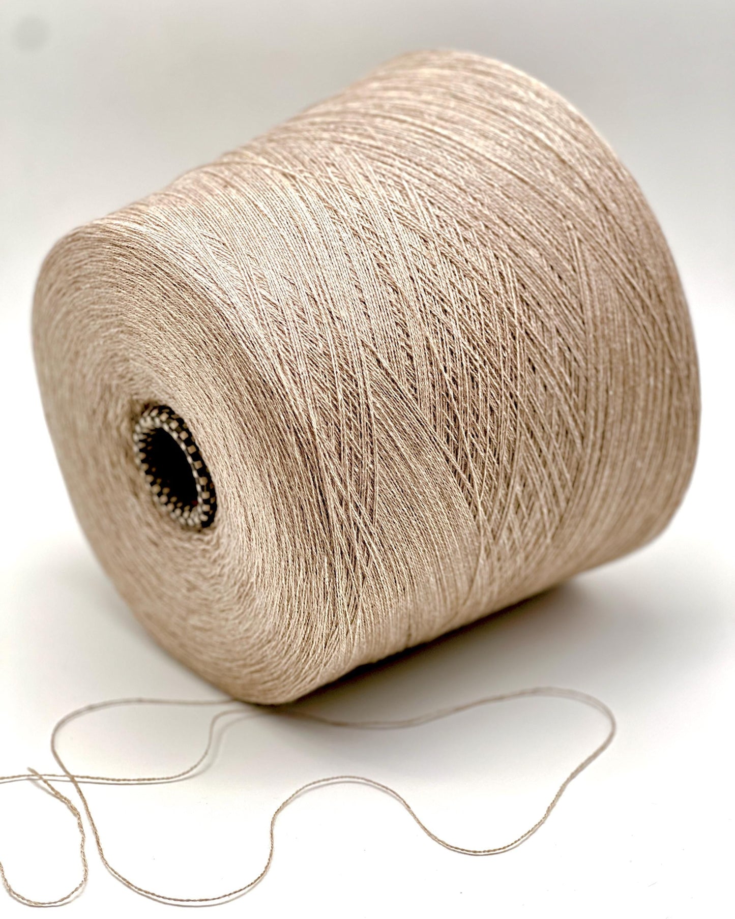 Spool of beige yarn on a white background
