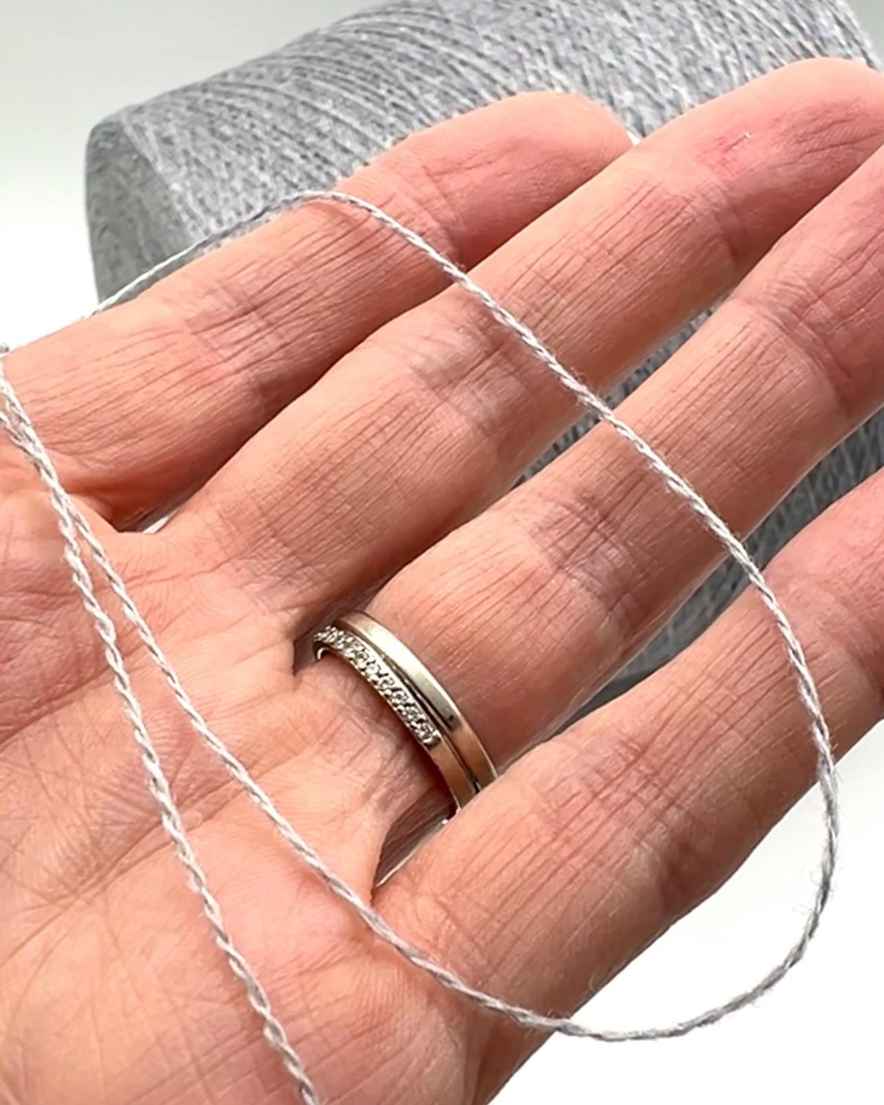 Hand wearing a silver ring with a plain background