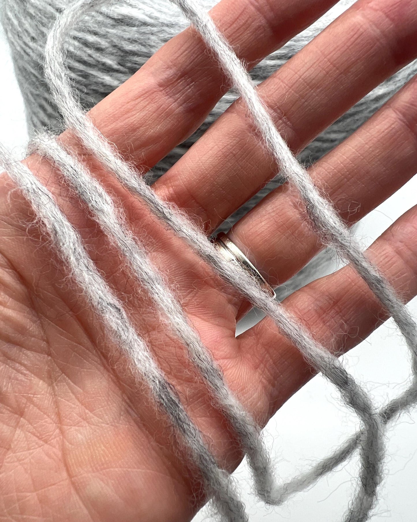 Close-up of a hand holding gray yarn