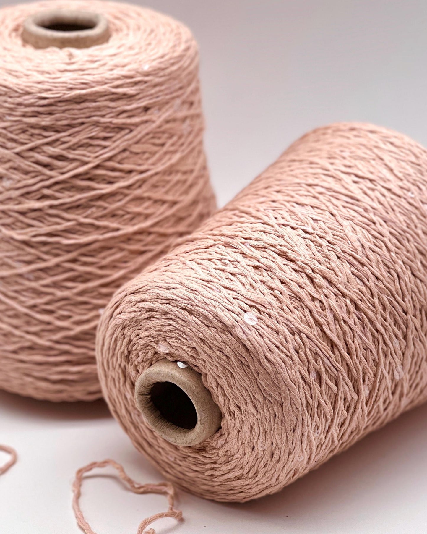 Two spools of beige yarn on a light background