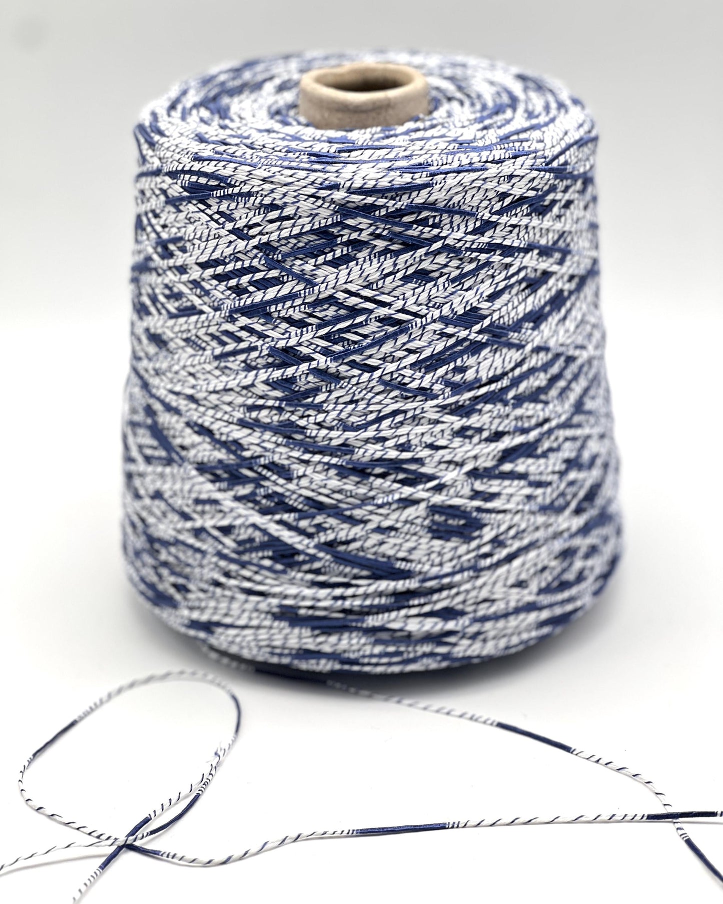 Spool of blue and white yarn on a light gray background