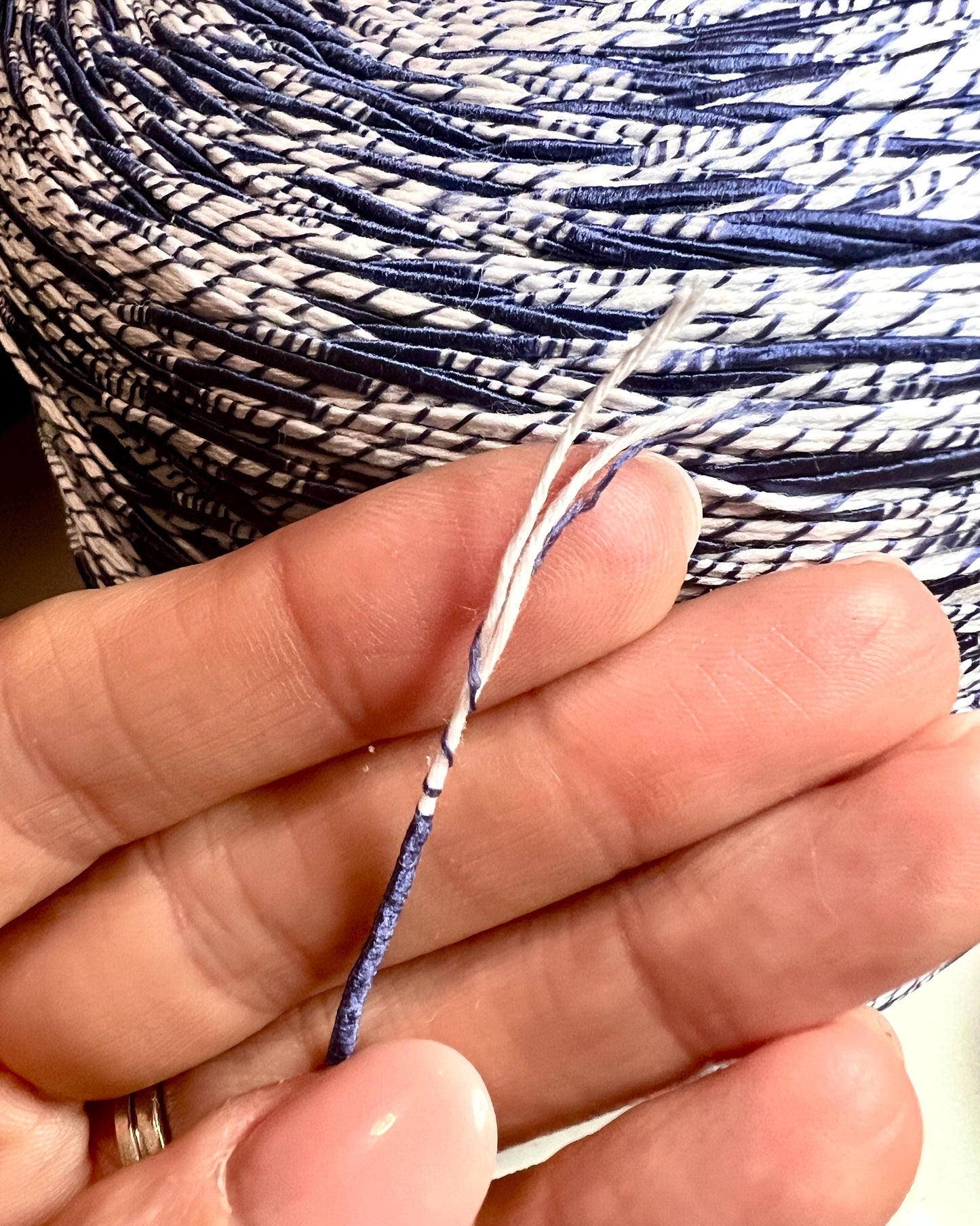 Close-up of hands holding a ball of blue and white yarn.