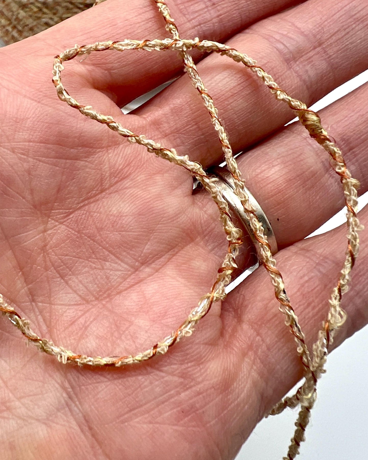 Gold chain held in a hand against a neutral background