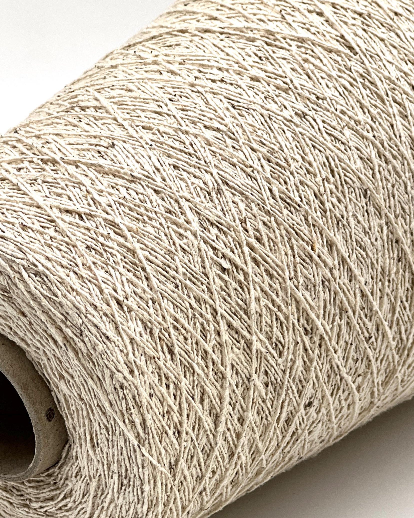 Close-up of a roll of beige yarn on a white background