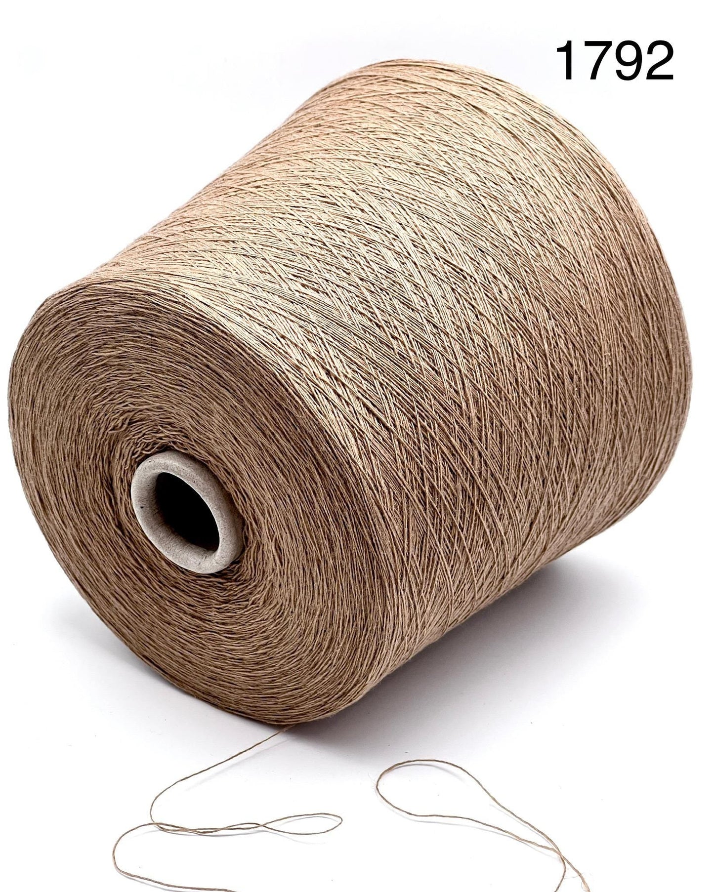 Spool of beige yarn with a needle on a white background