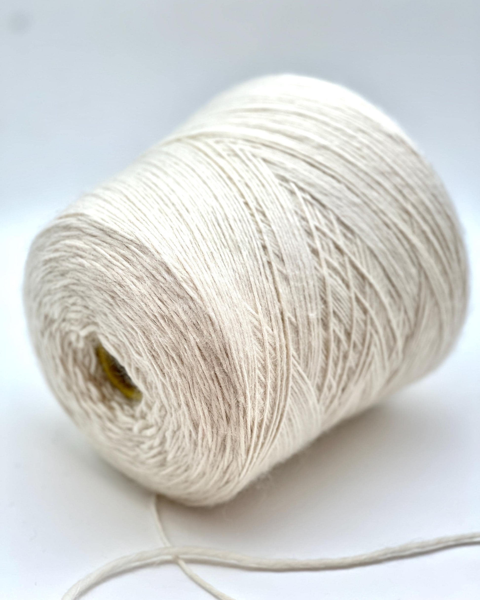Spool of white yarn on a white background