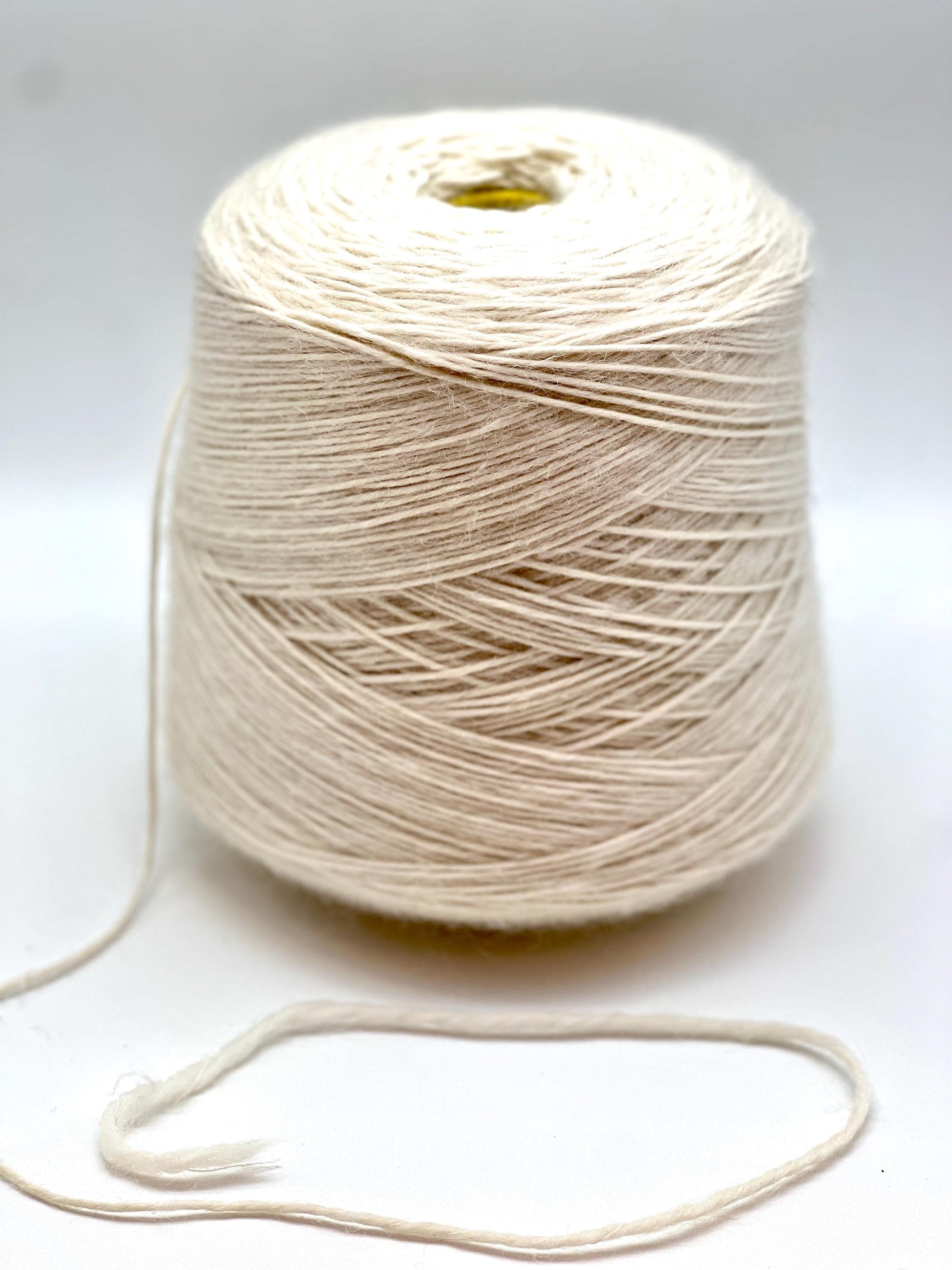 Spool of beige yarn on a white background