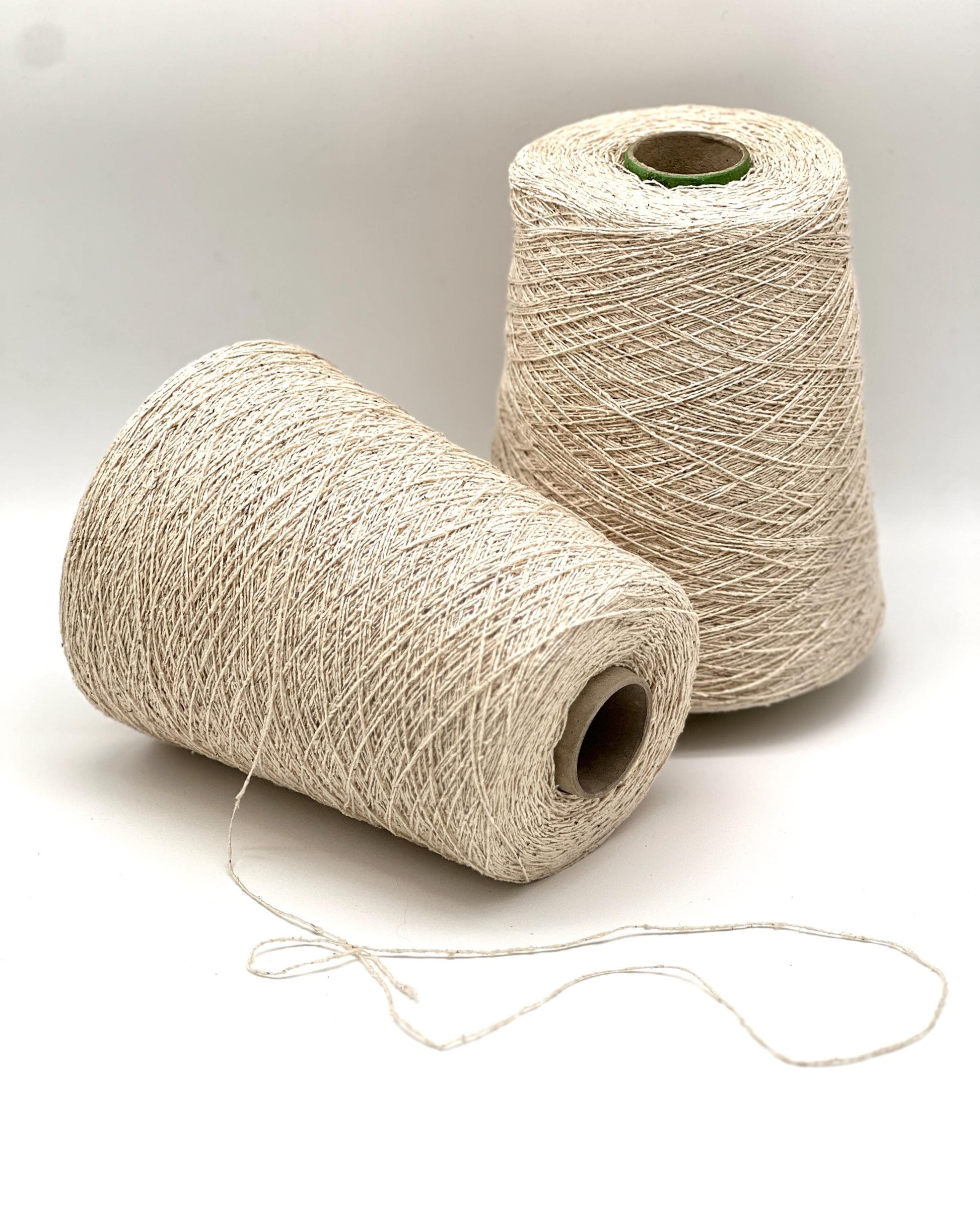 Two spools of beige thread on a white background