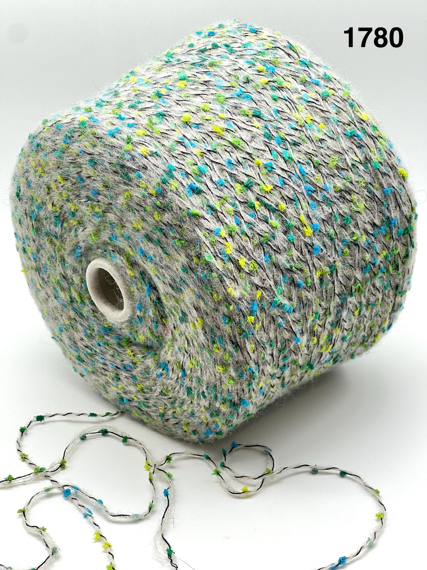 COLOR - 1780 GREY MULTI - Spool of multicolored yarn with a string of yarn loops on a white background
