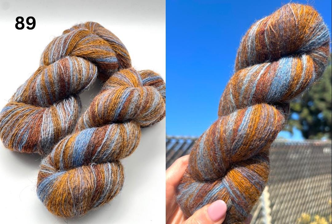 Multicolored skein of yarn on a white background with a blue sky and tree in the background.