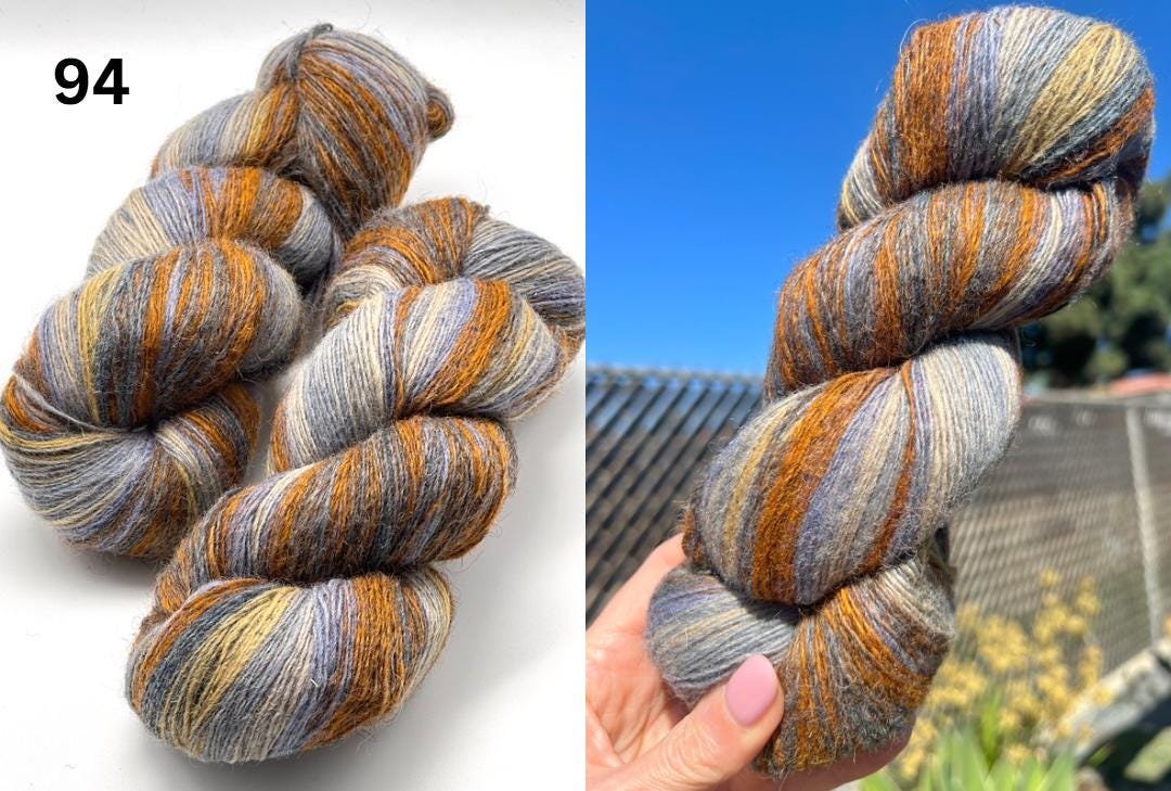 Multicolored skein of yarn on a white background with a close-up of a hand holding the yarn.