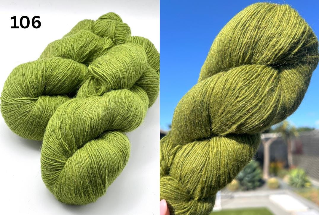 Two skeins of green yarn with a blurred outdoor background