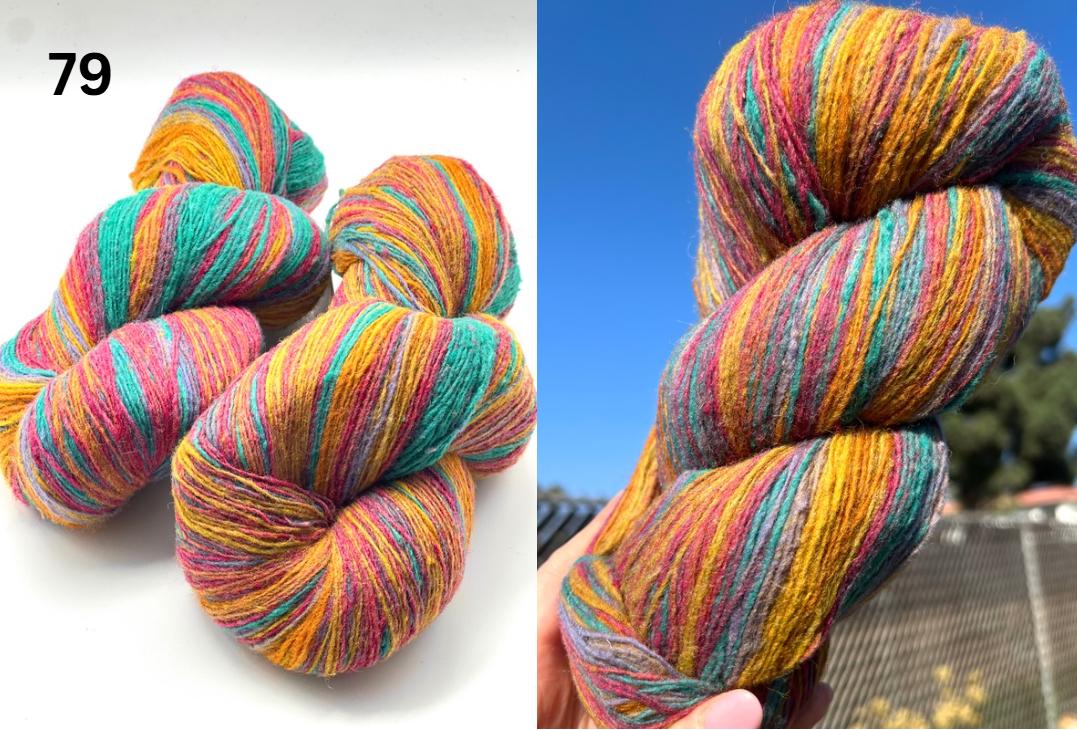 Multicolored yarn skeins on a white background and held against a blue sky.