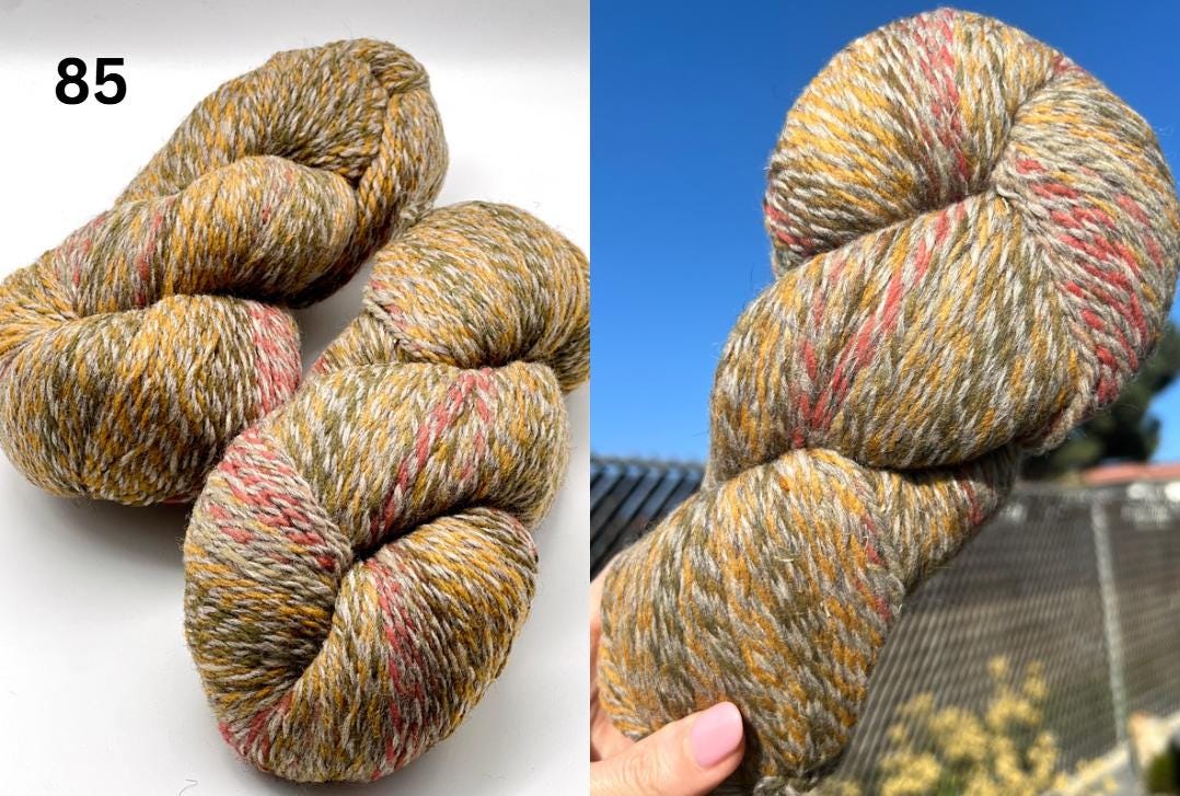 Two skeins of multicolored yarn on a white background and held against a blue sky.
