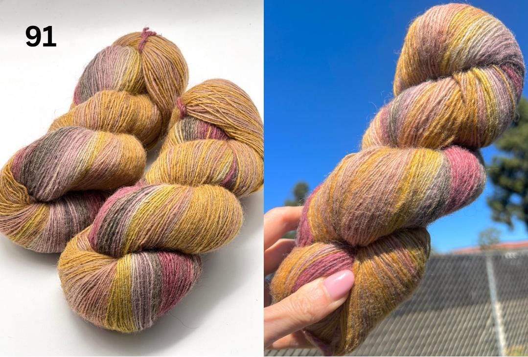 Multicolored yarn skeins on a white background and held in a hand with a blue sky and trees in the background.