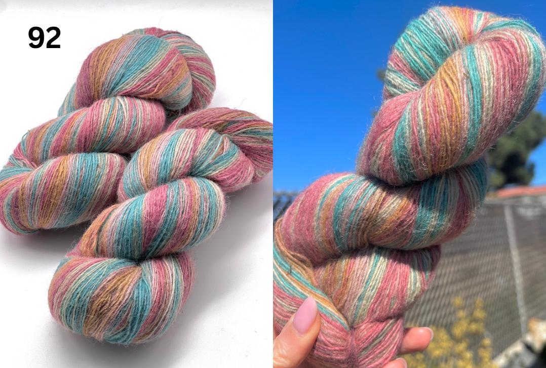 Multicolored skein of yarn on a white background with a blue sky and trees in the background.