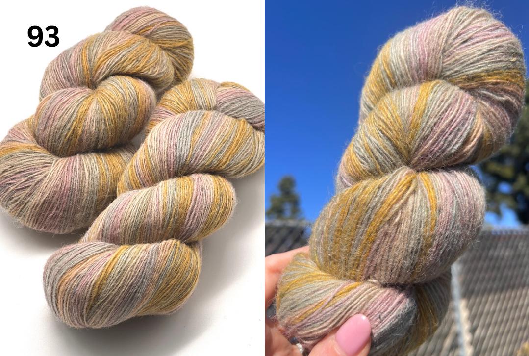 Multicolored skein of yarn on a white background with a blue sky and trees in the background.