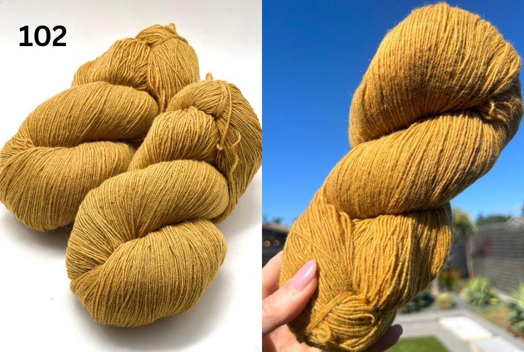 Mustard yellow yarn skeins on a white background and held in a hand with a blurred outdoor background.