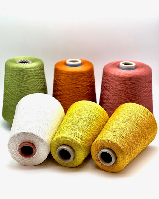 Six spools of yarn in various colors on a white background