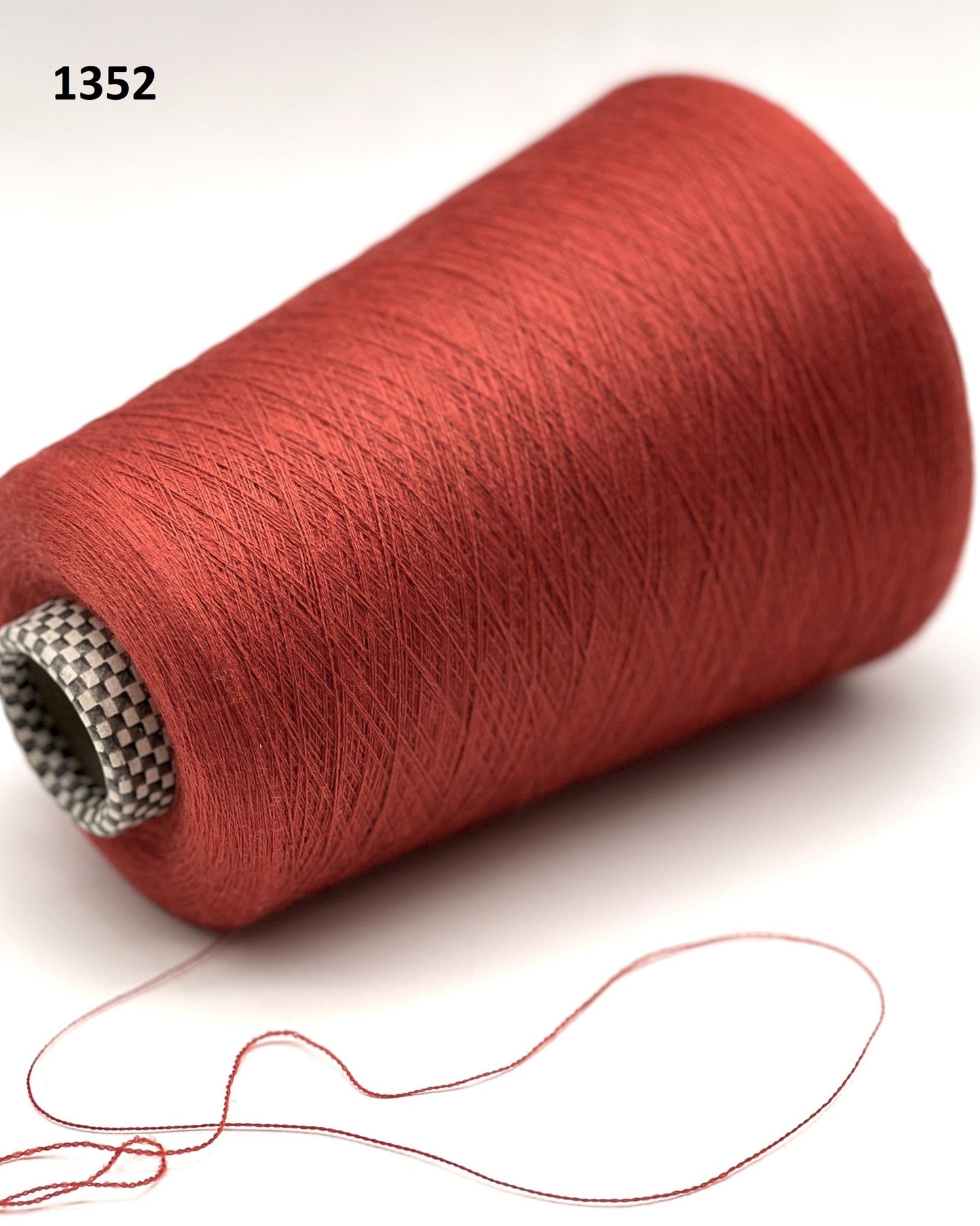Red spool of thread with a small thread snippet on a white background