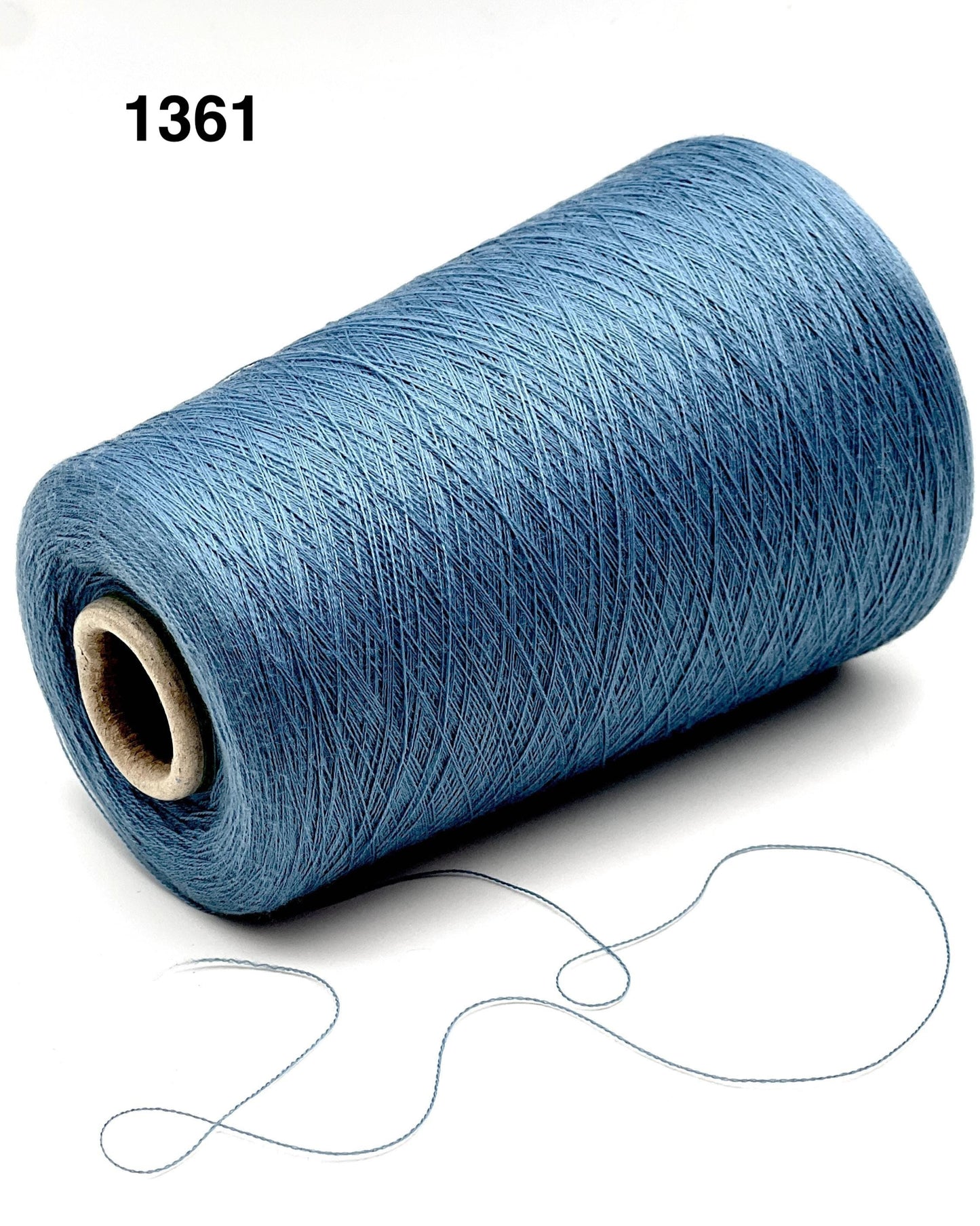 Blue spool of thread with a small piece of thread on a white background