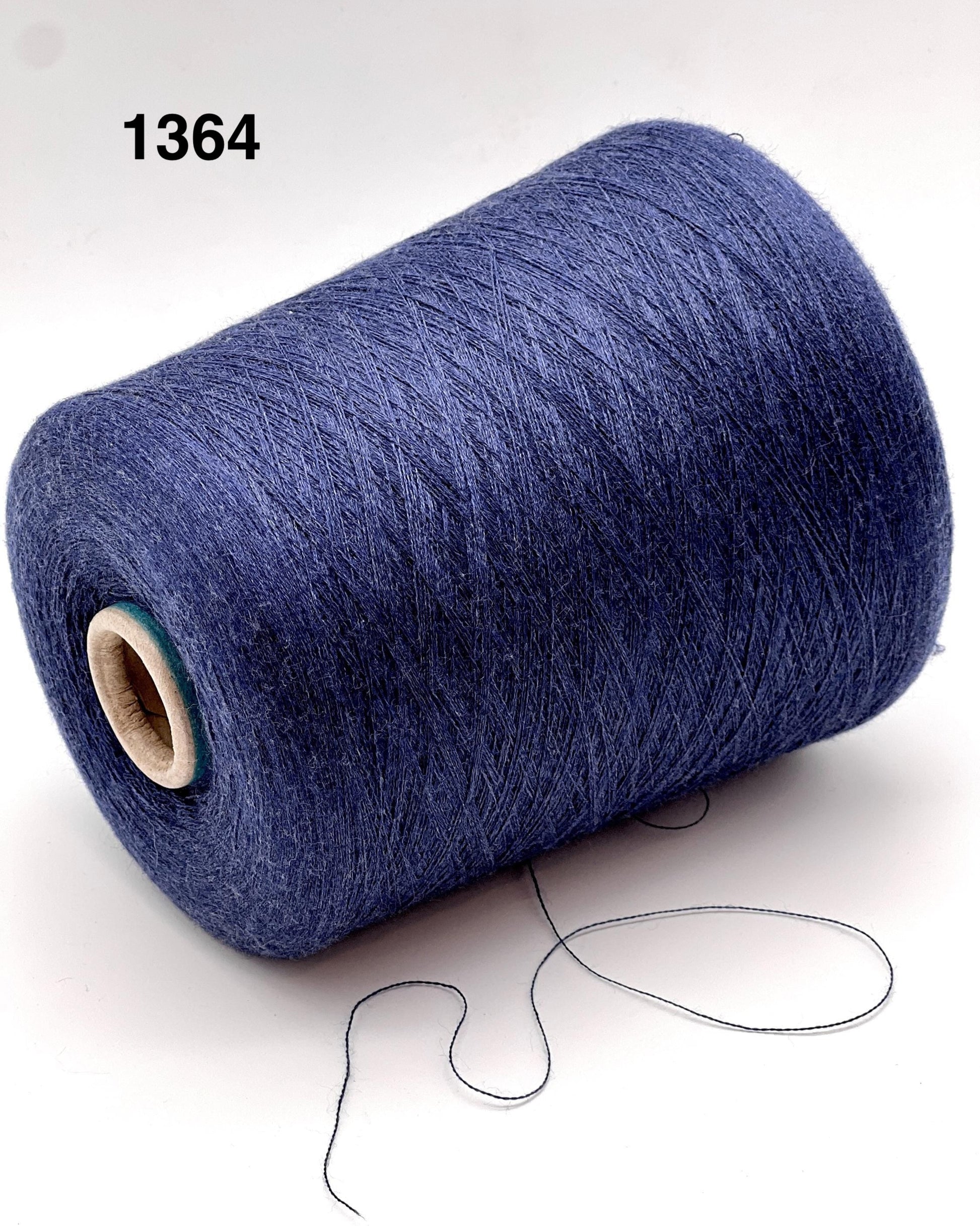 Blue spool of yarn with a small amount of yarn hanging out on a white background