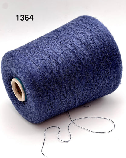 Blue spool of yarn with a small amount of yarn hanging out on a white background