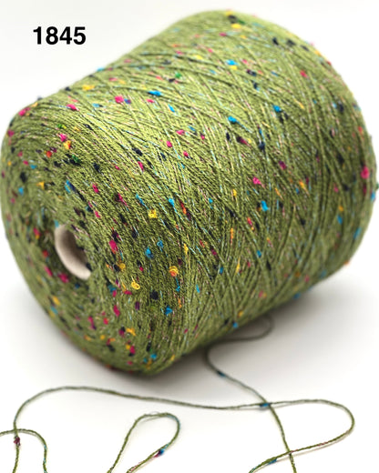 Spool of green yarn with multicolored specks on a white background