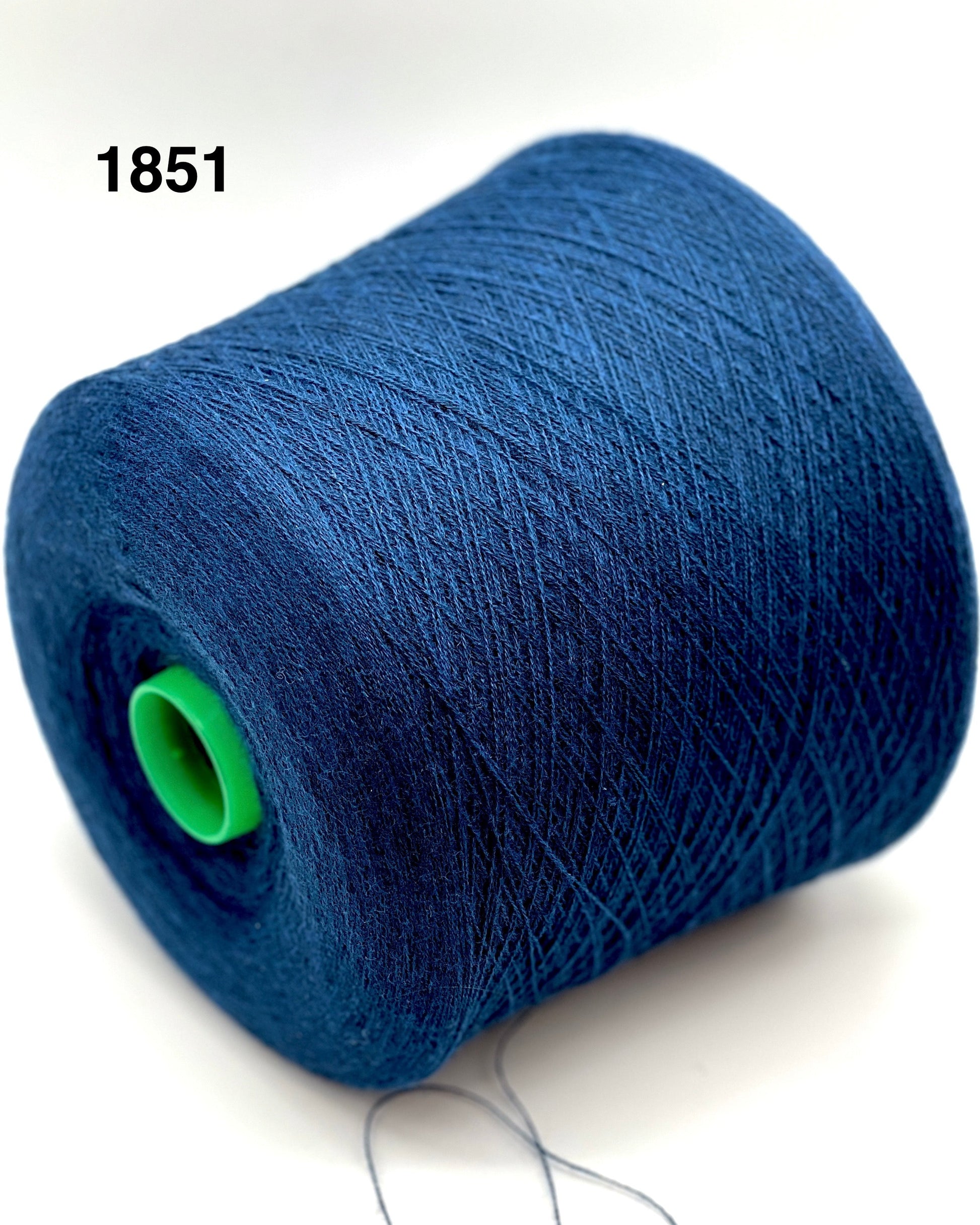 Blue spool of thread with a green knot on a white background