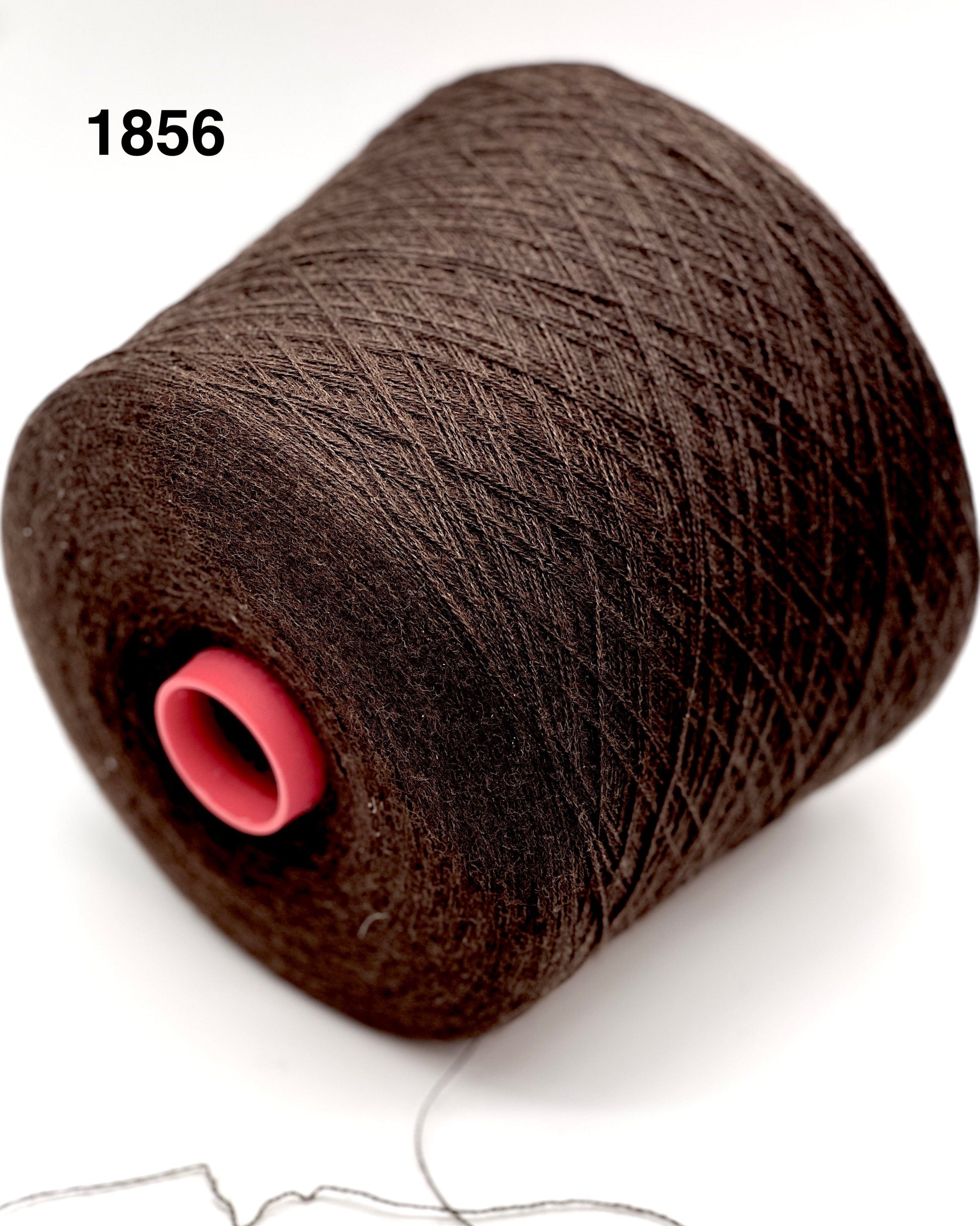 Spool of dark brown thread with a pink core on a white background
