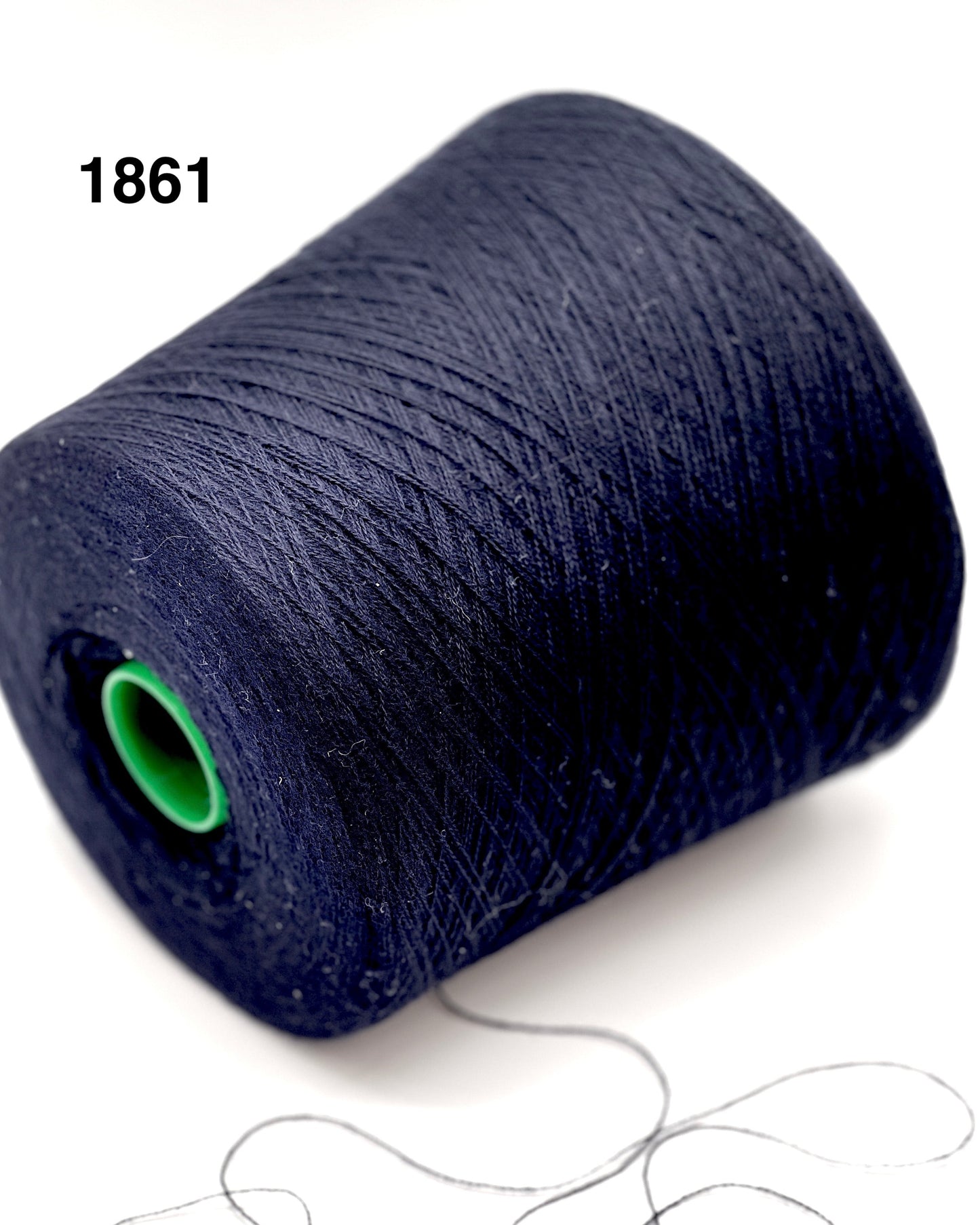 Spool of dark blue thread with a green core on a white background