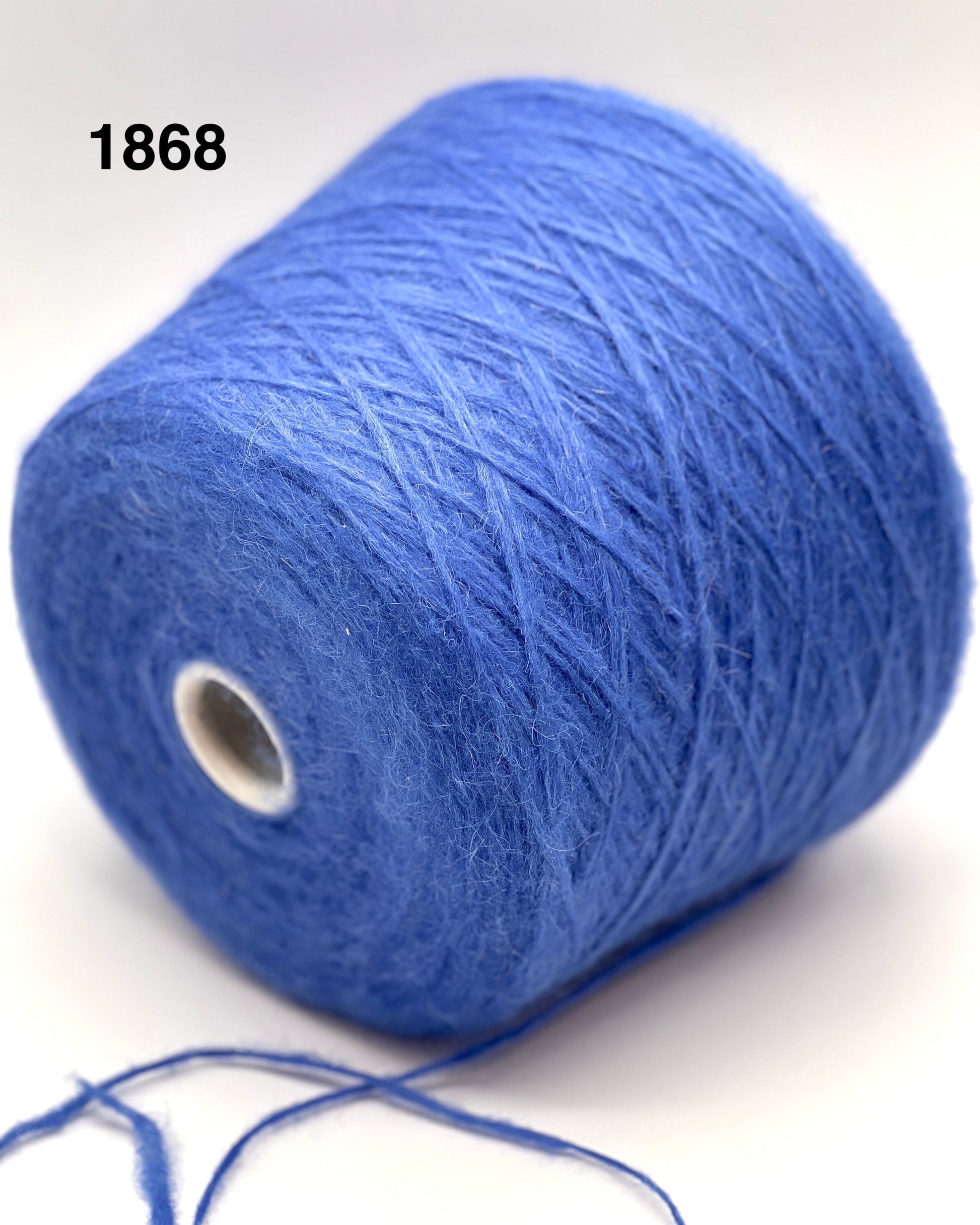 Blue yarn spool with a small amount of yarn on a white background
