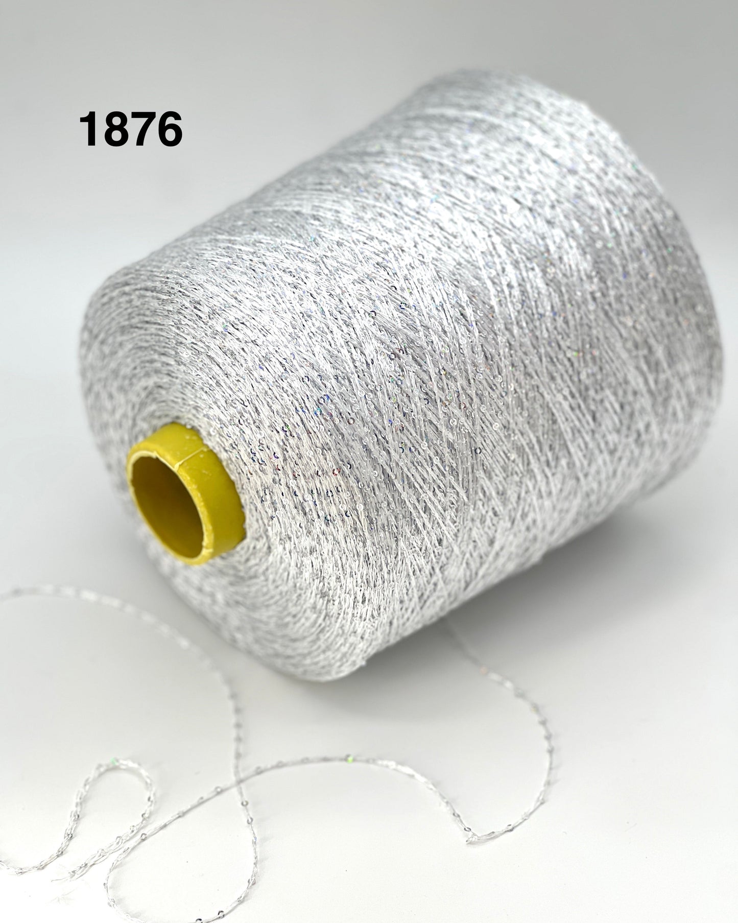 Spool of silver yarn with a yellow label on a white background