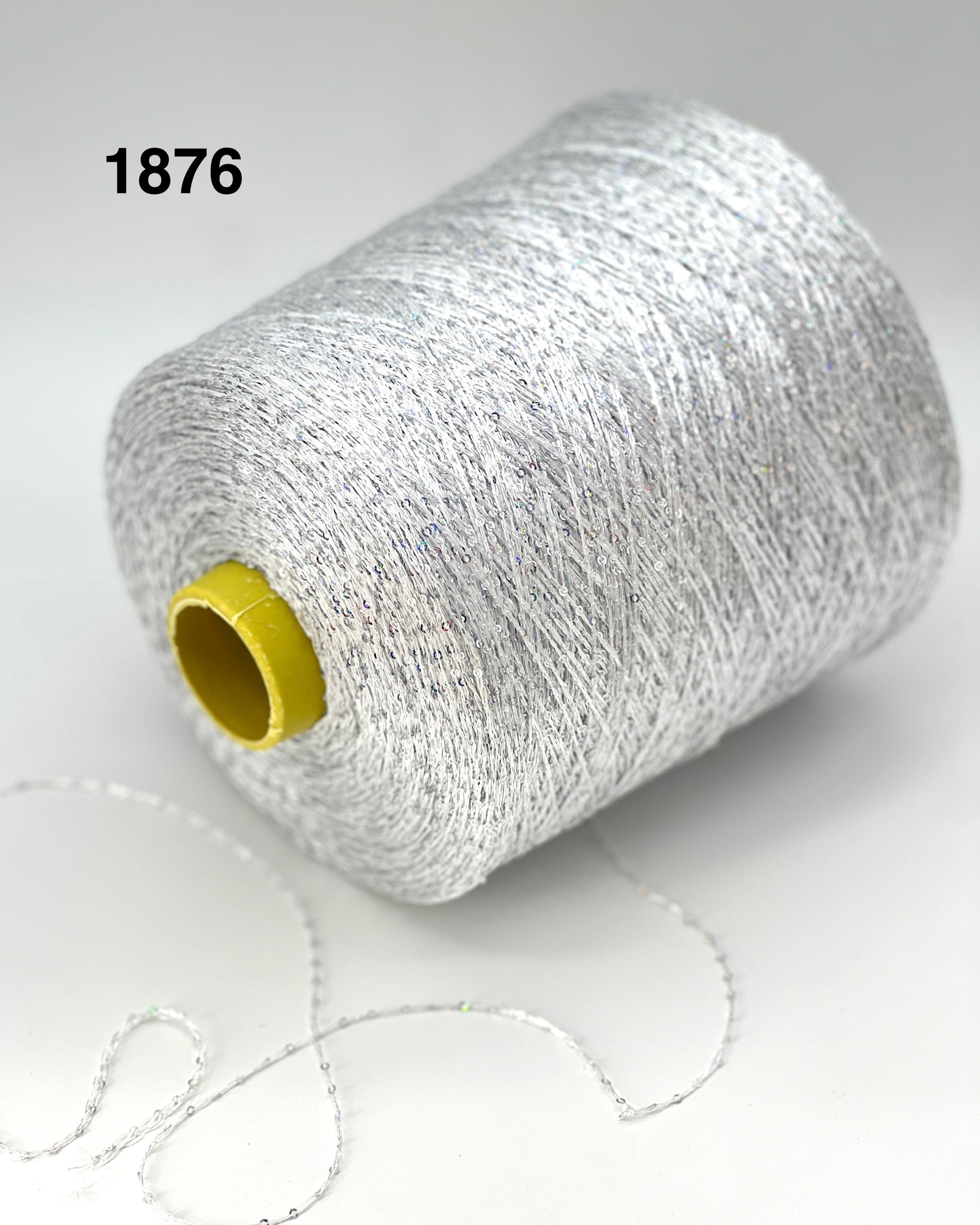 Spool of silver yarn with a yellow label on a white background