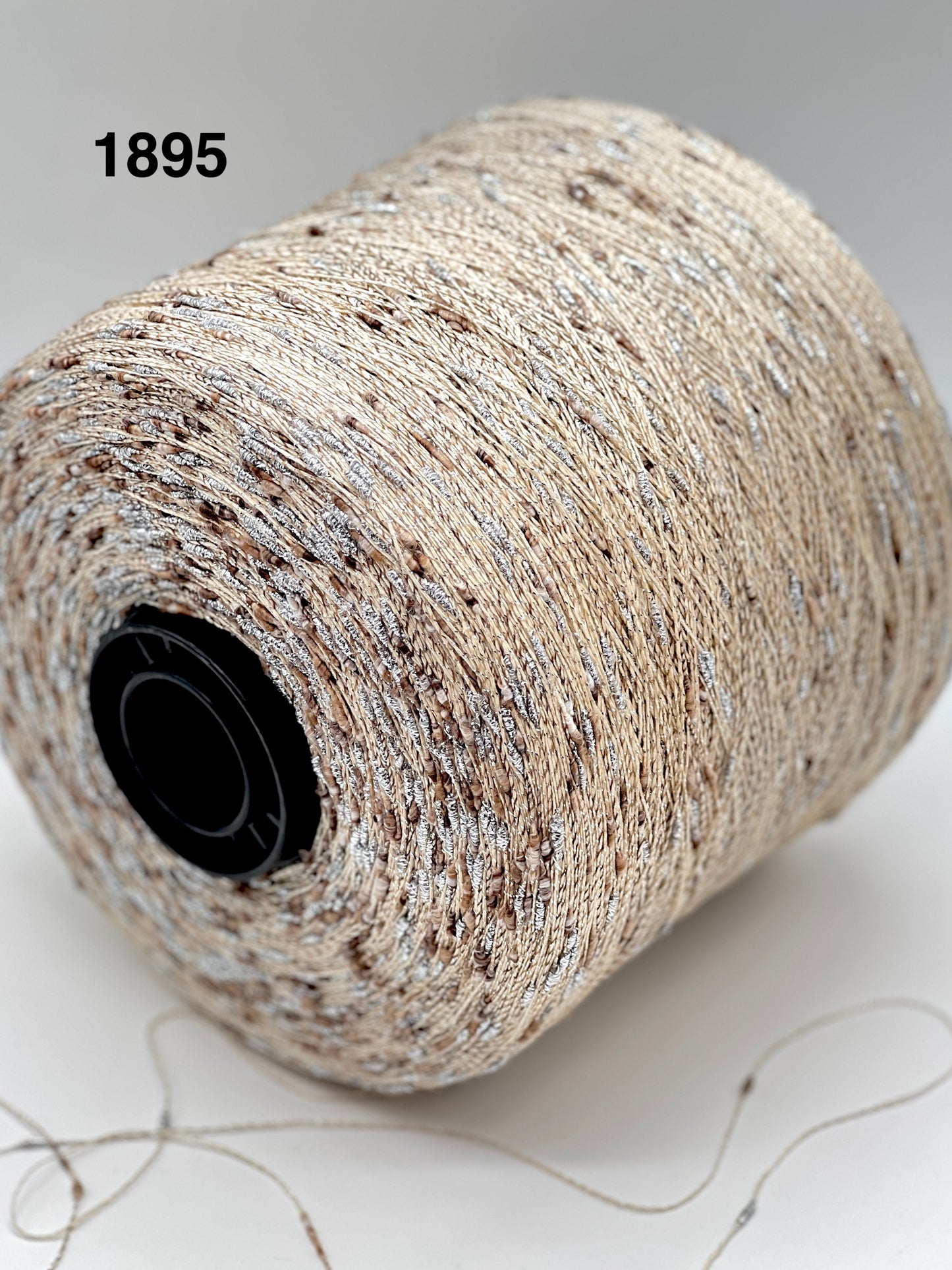 Spool of beige thread with a black core on a light background