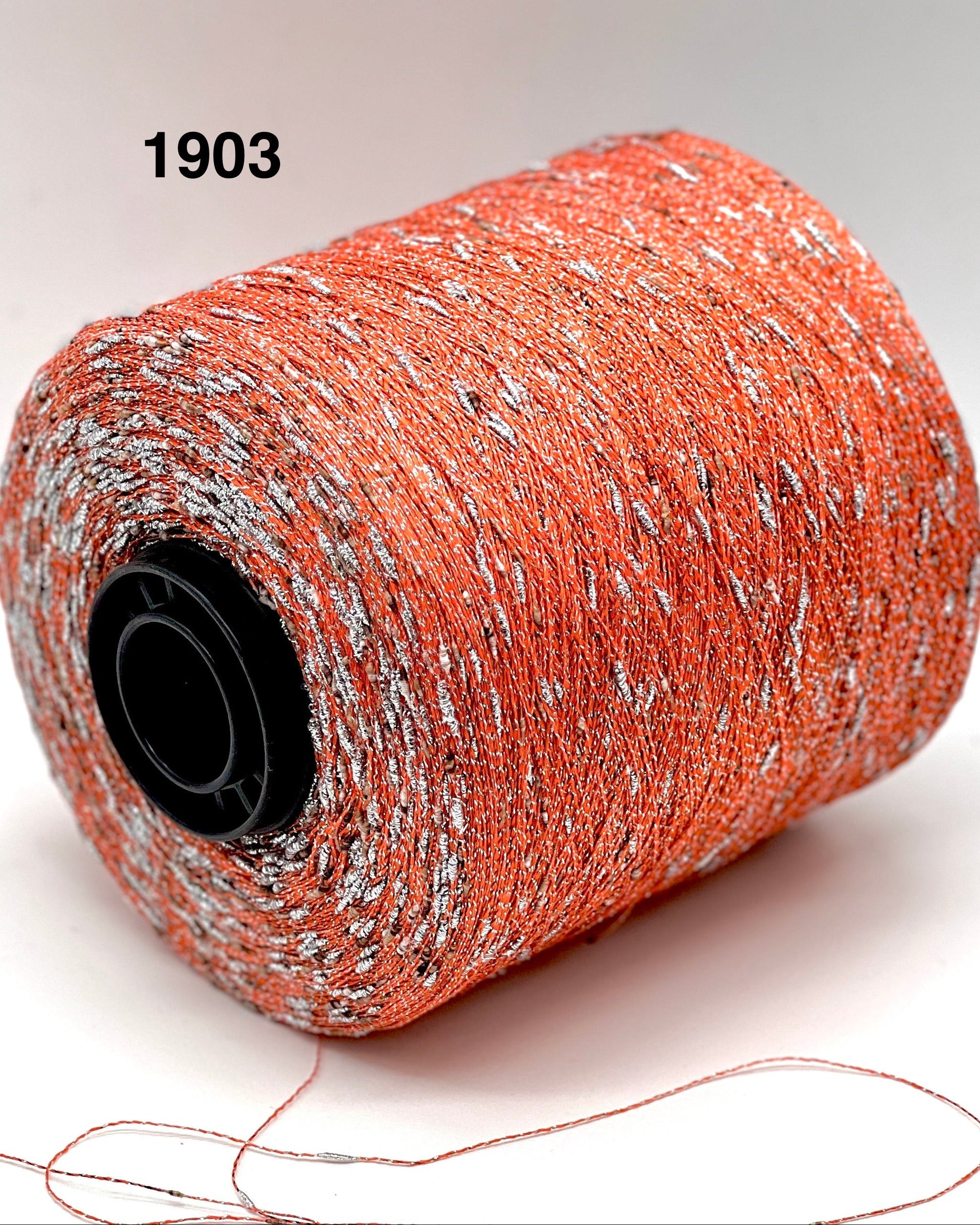 Spool of orange thread with speckles on a white background