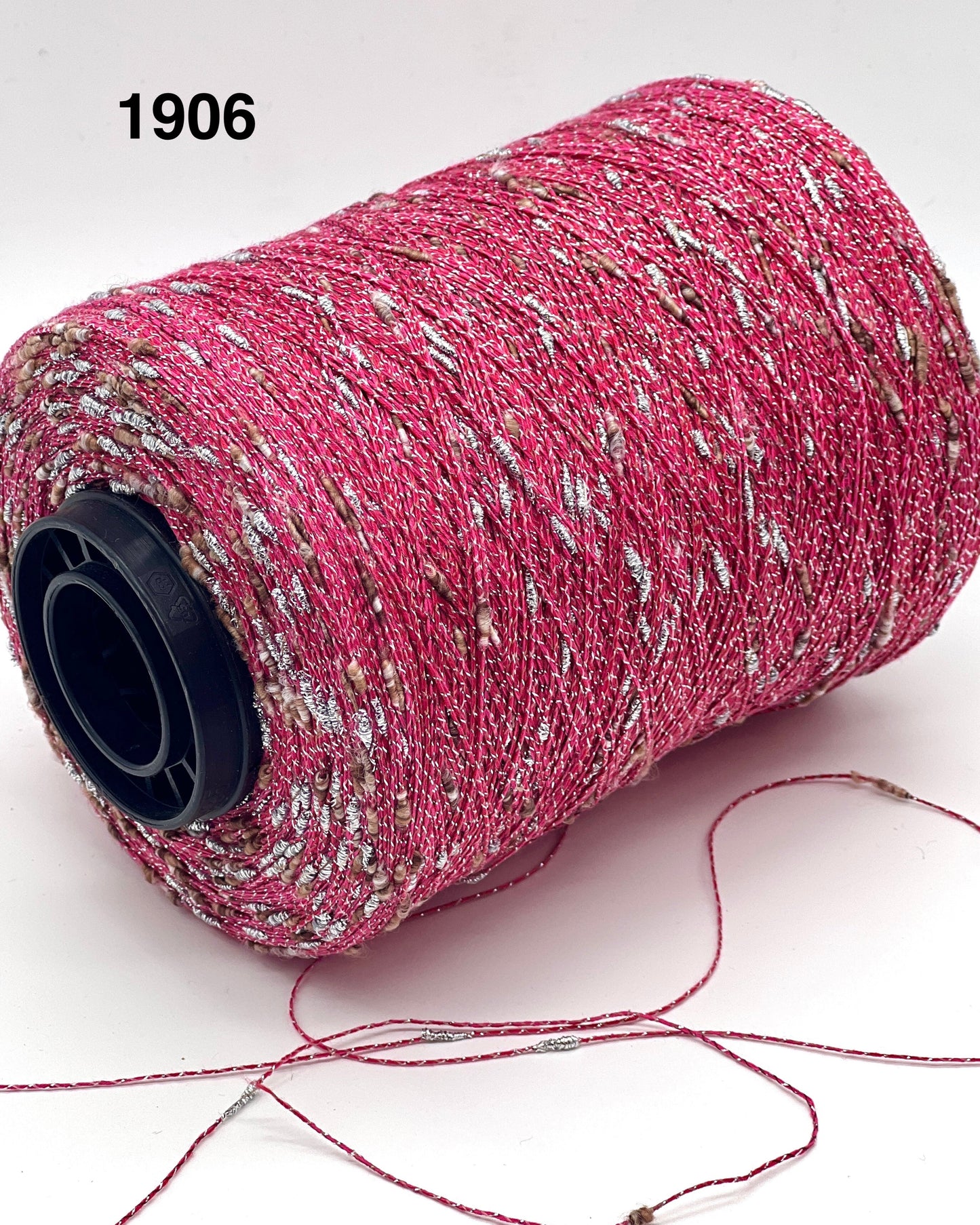 Spool of pink thread with speckles on a white background