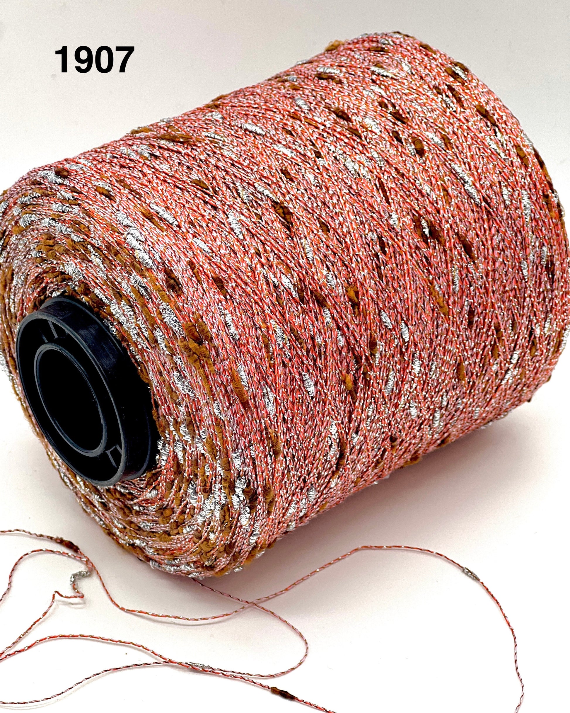 Spool of pink glittery thread with a black spool on a white background