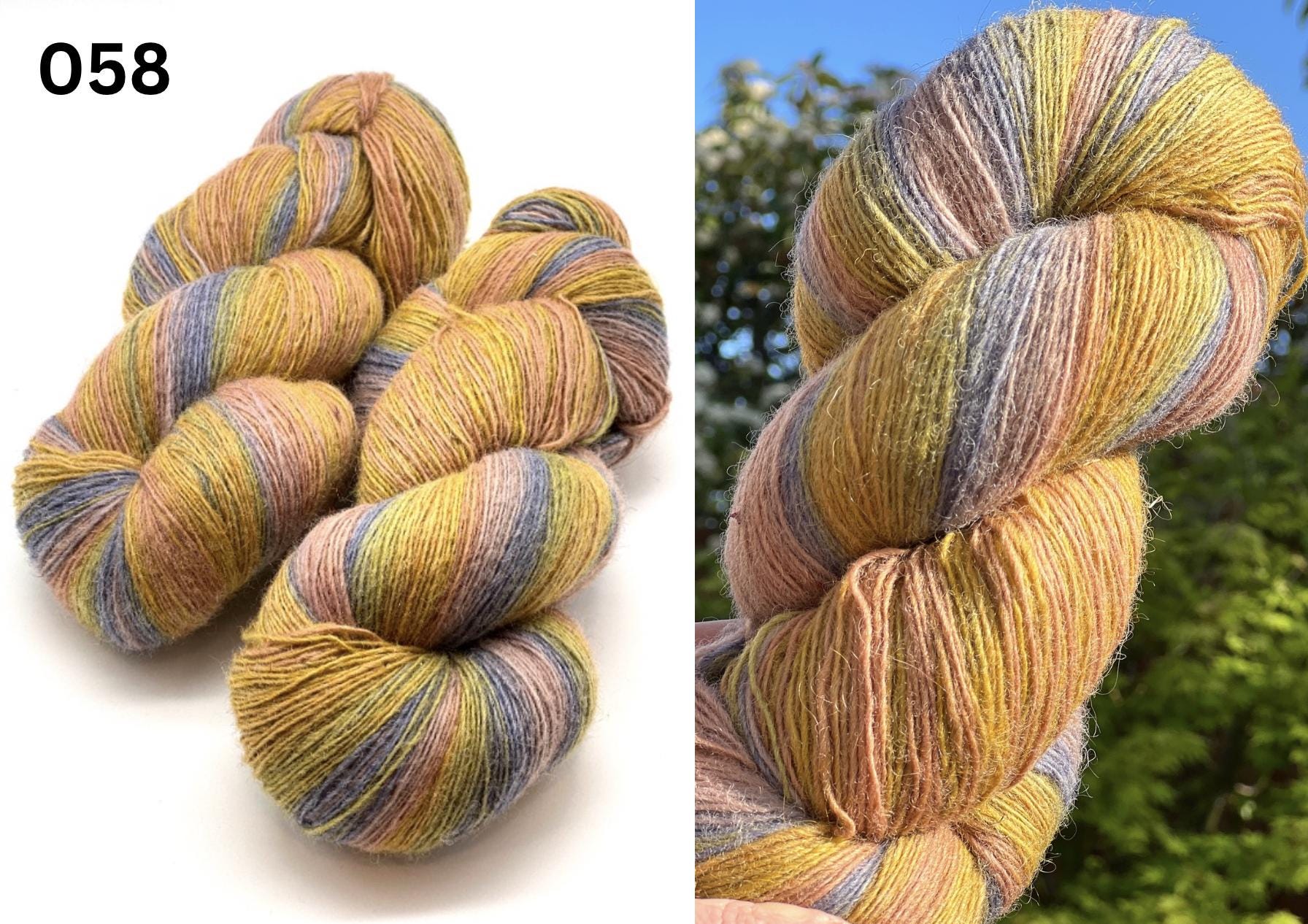 Small-batch dyed heritage skeins of 100% Latvian Dark-Headed Sheep Wool in earthy multicolor gradients like Green-Brown #052. The image shows the rustic single-ply texture and the sheep breed origin, representing the authentic wool traditions of Paces Vilnas Fabrika, Latvia. Available at iDOKNiT.com.