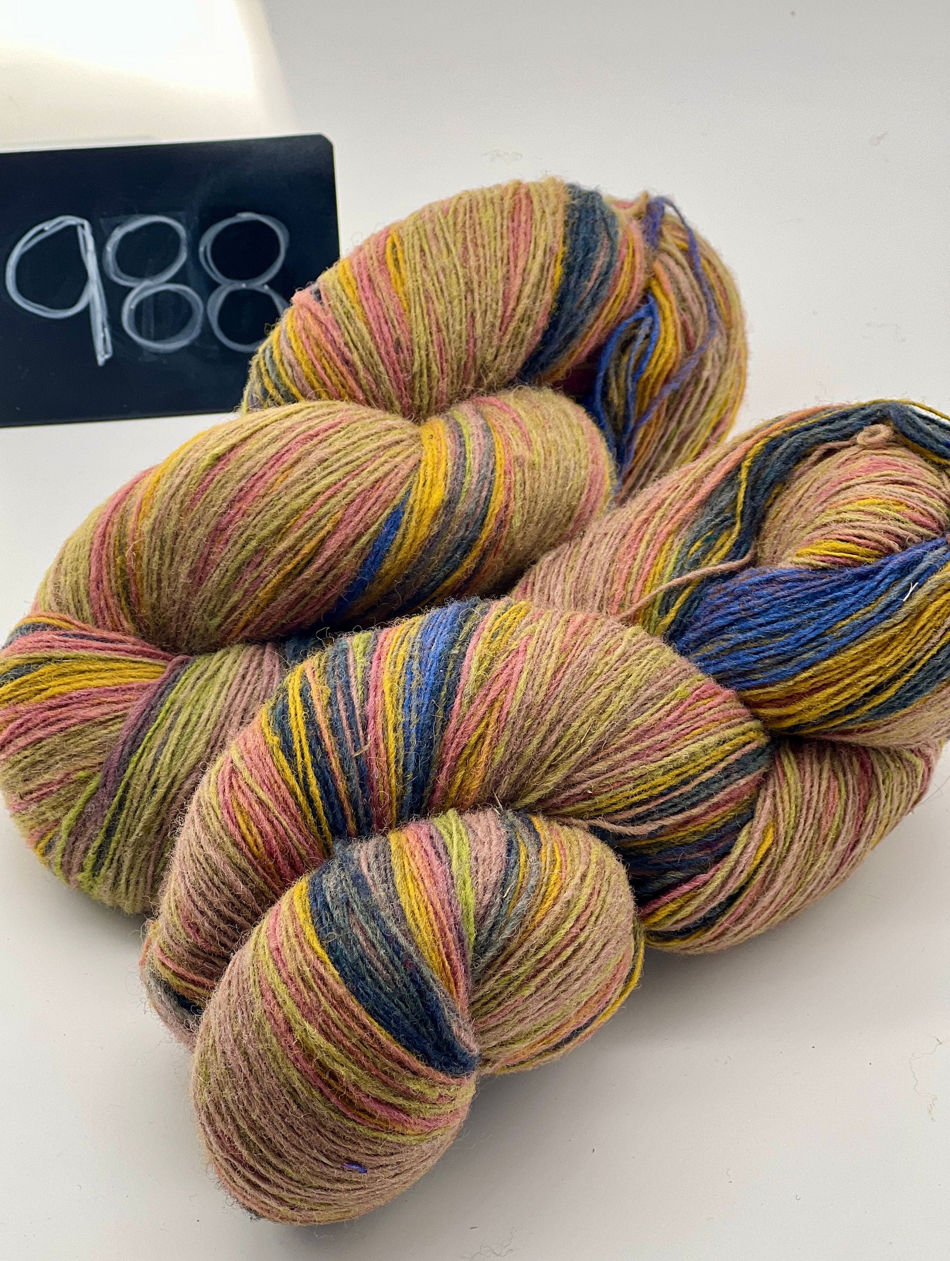 Large rustic skeins of DUNDAGA 6/2 yarn showing vibrant, multi-colored transitions in shades of purple, orange, green, and blue. This traditional Latvian wool and merino blend features a natural texture. Available in various weights at iDOKNiT.com.